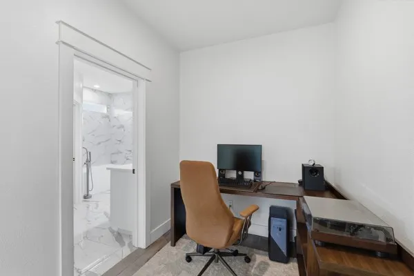 Hardwood-finish flooring, built-in L-shaped desk, white walls, and a doorway with layered trim molding
