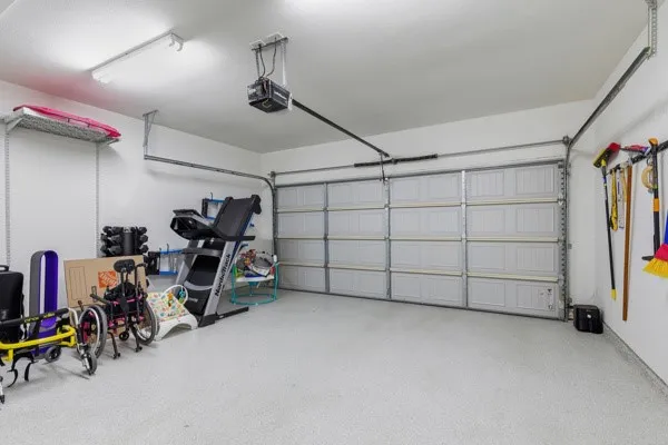 Garage with a light-colored epoxy floor, overhead fluorescent lighting, and a paneled garage door