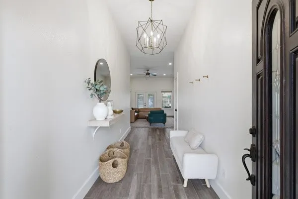 Entryway featuring a dark wood-finish front door with decorative glass, wood-finish tile flooring, and a contemporary geometric chandelier