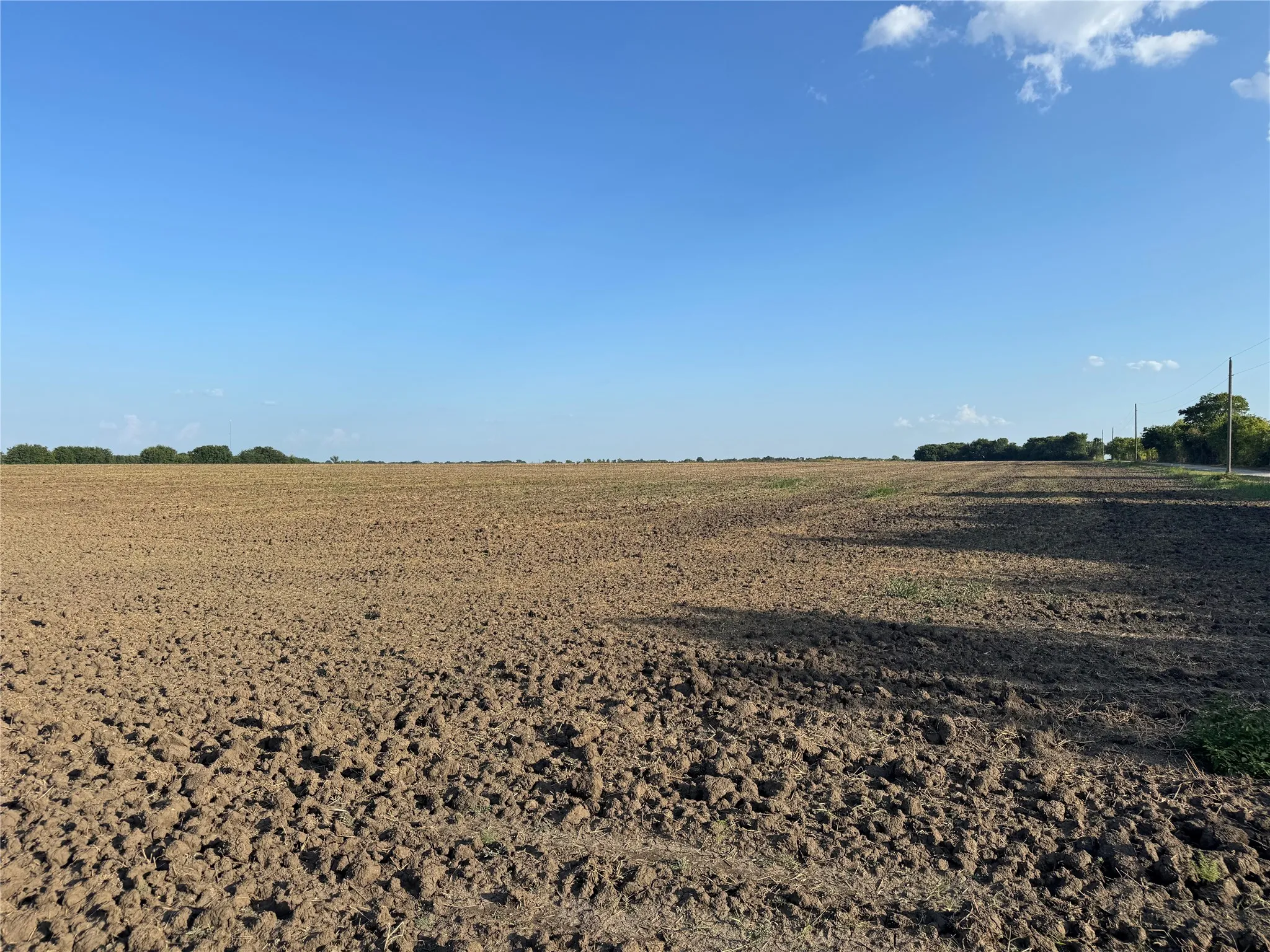 Expansive cleared land featuring cultivated soil and distant tree lines