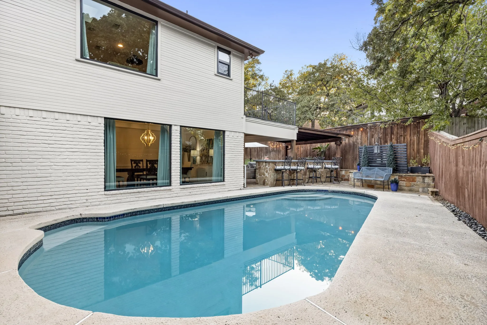 Backyard oasis featuring an in-ground swimming pool, concrete patio, and a covered outdoor kitchen with a built-in bar
