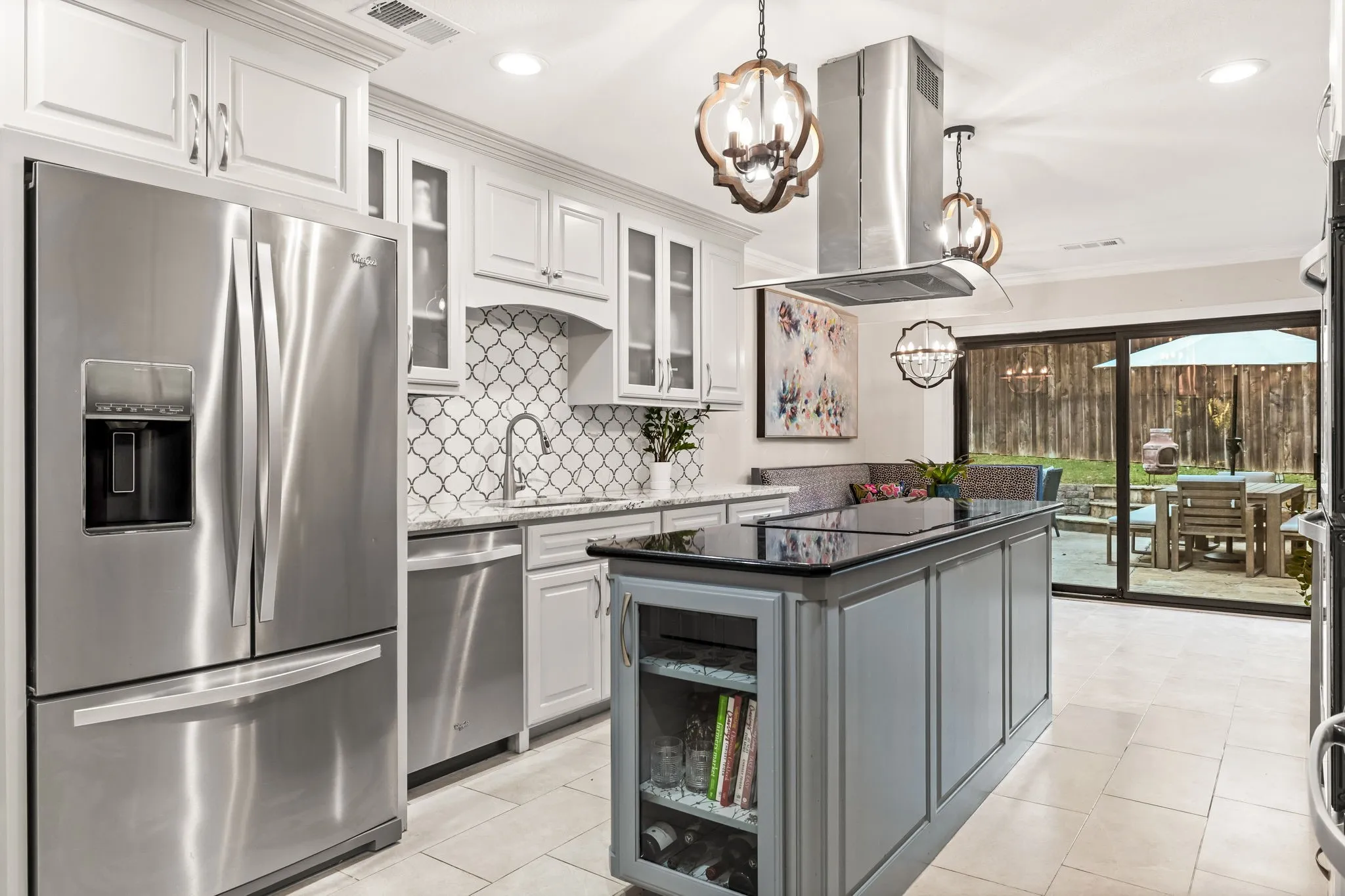 Gourmet kitchen featuring stainless steel appliances, a central island with a dark countertop, white shaker-style cabinetry, and a patterned tile backsplash
