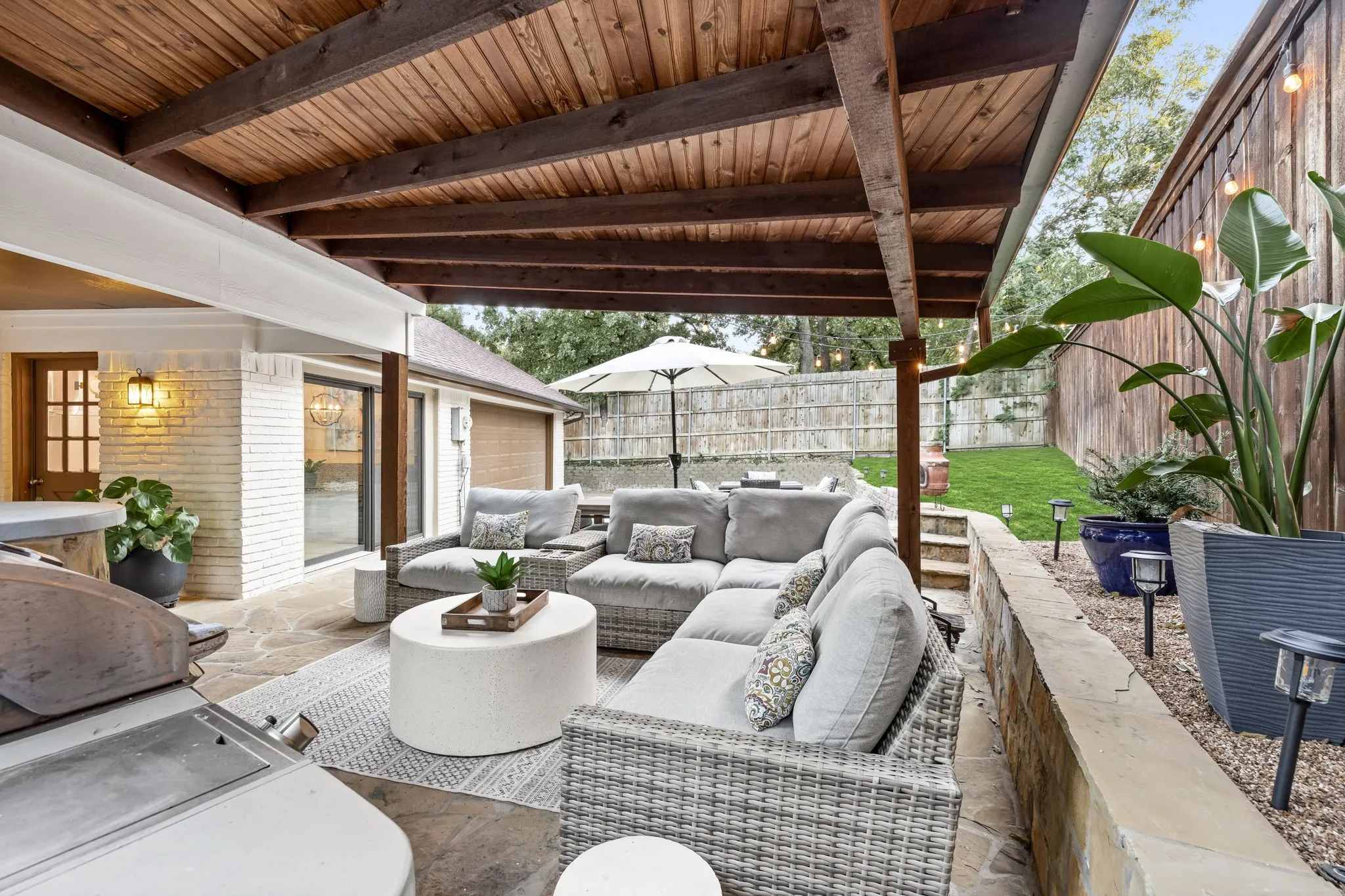 Covered patio featuring a wood-plank ceiling, flagstone flooring, and a stone retaining wall