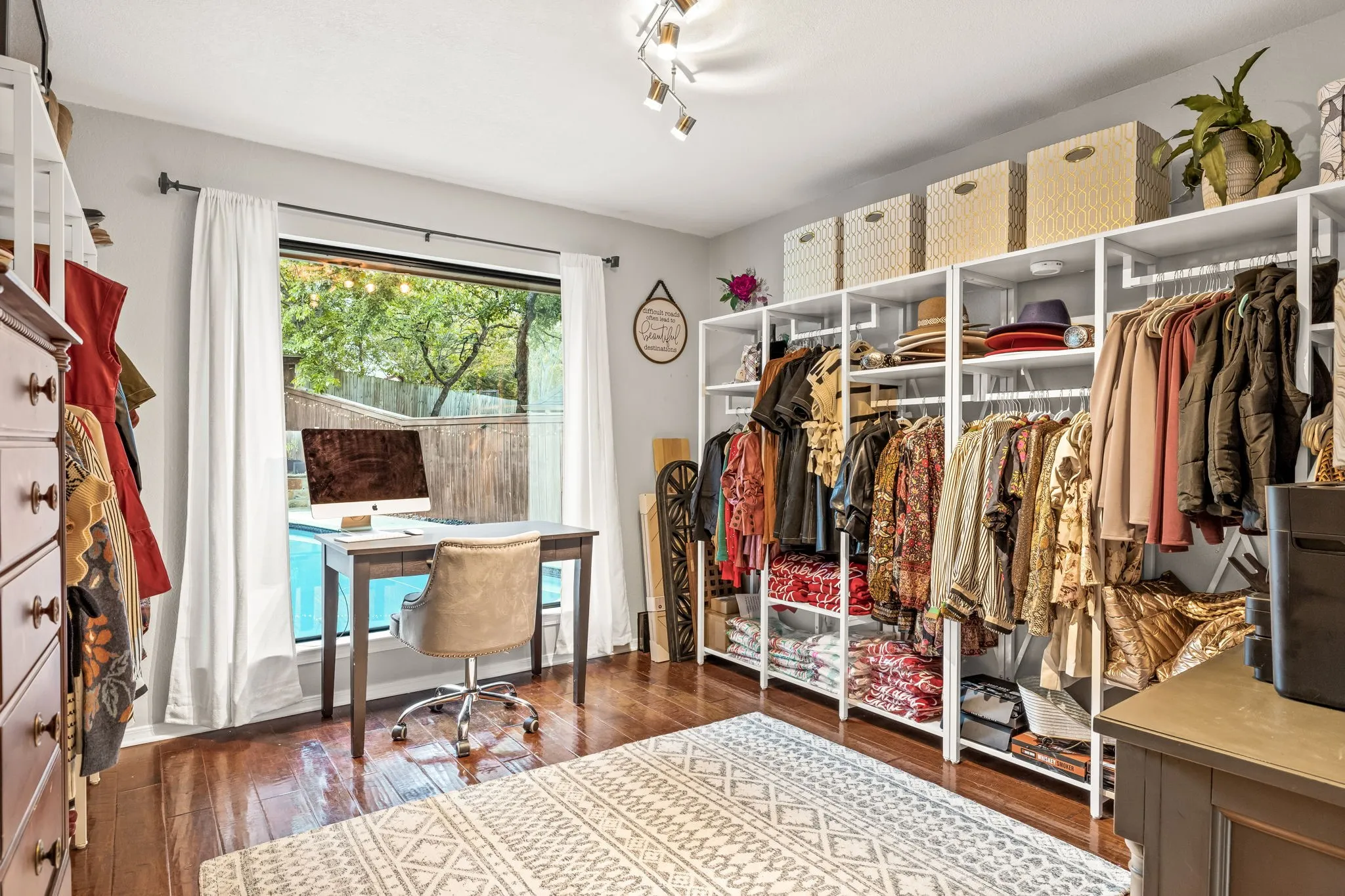 Hardwood-finish flooring, built-in shelving, track lighting, and a window with a pool view