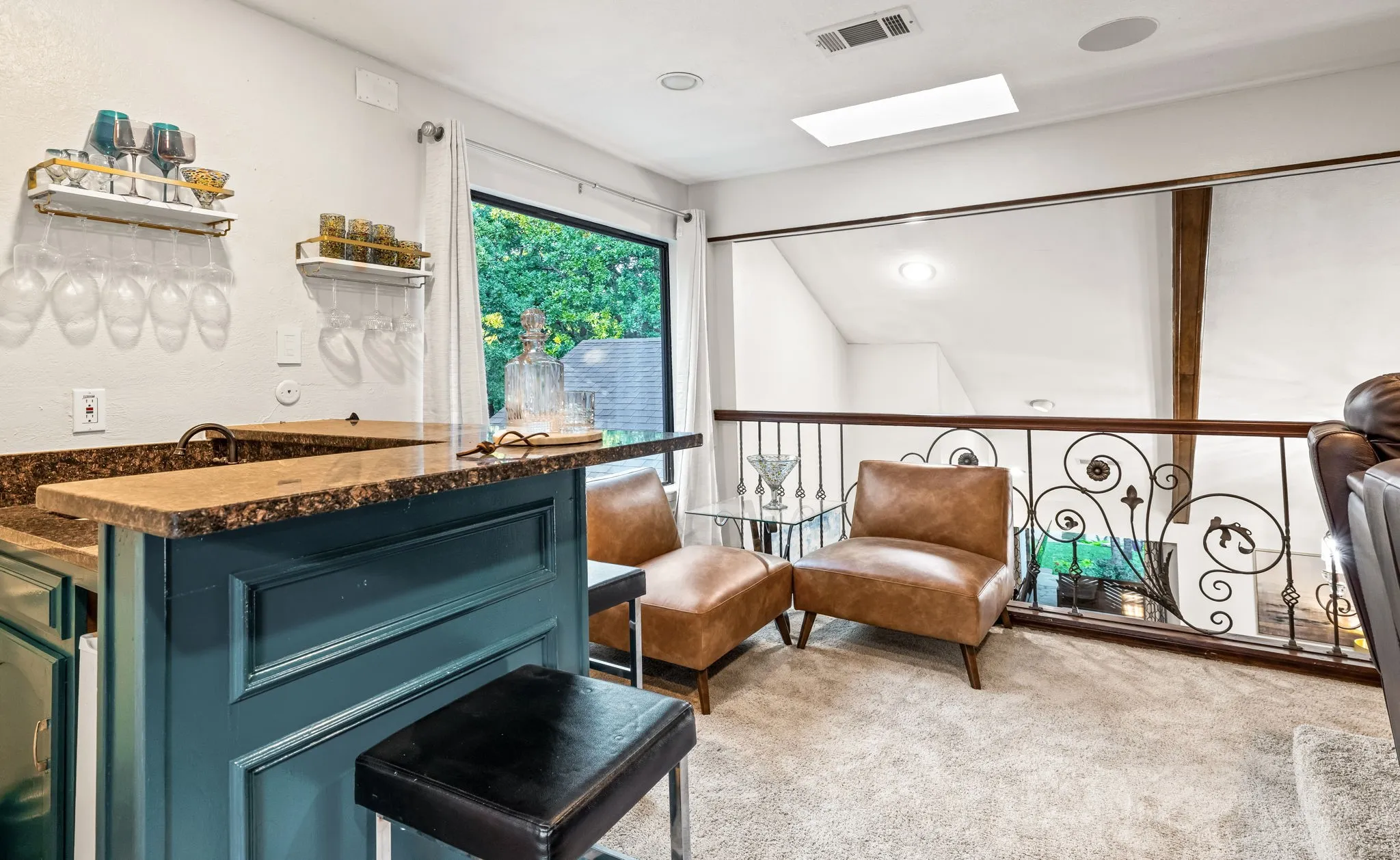 Loft area featuring a custom metal railing, a built-in bar with stone-finish countertops, recessed lighting, and a skylight
