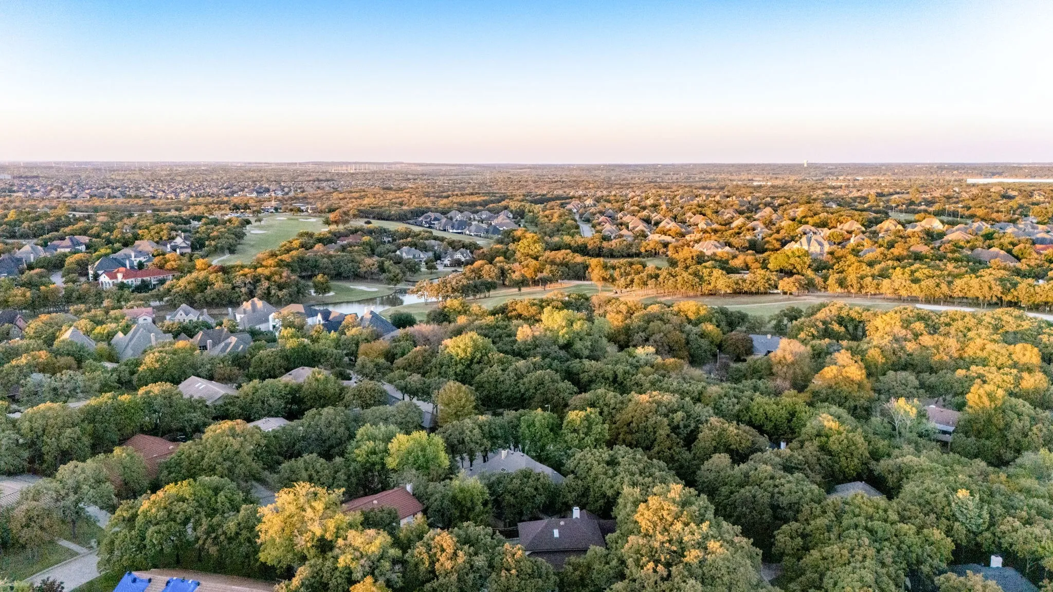Expansive treed landscape with residential properties and a distant golf course