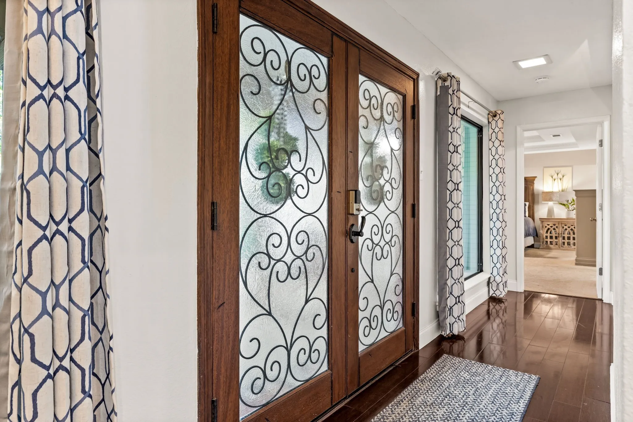 Wood-finish flooring, decorative glass double entry doors, and recessed ceiling lighting