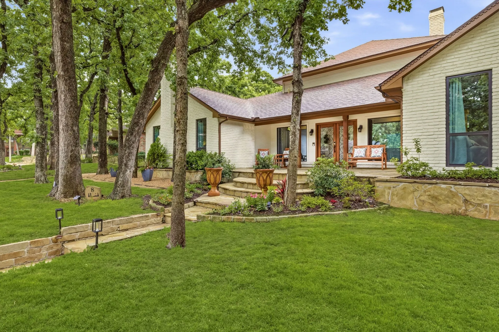 Expansive lawn featuring mature trees and a stone pathway with integrated lighting
