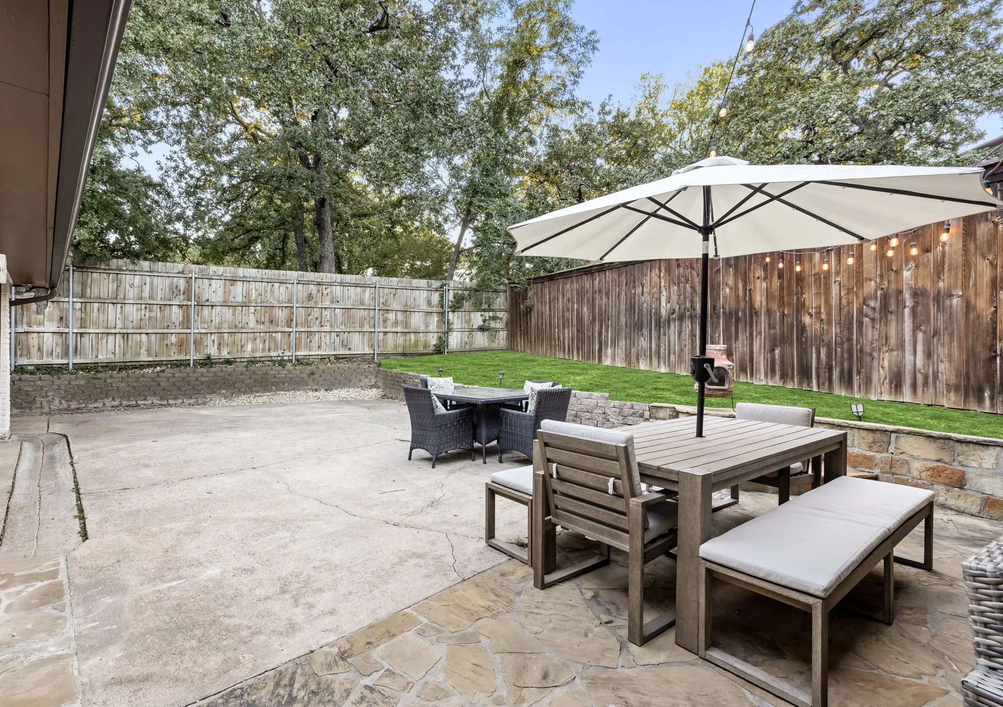 Expansive backyard featuring a combination of concrete and flagstone patios, a manicured lawn, and natural wood fencing