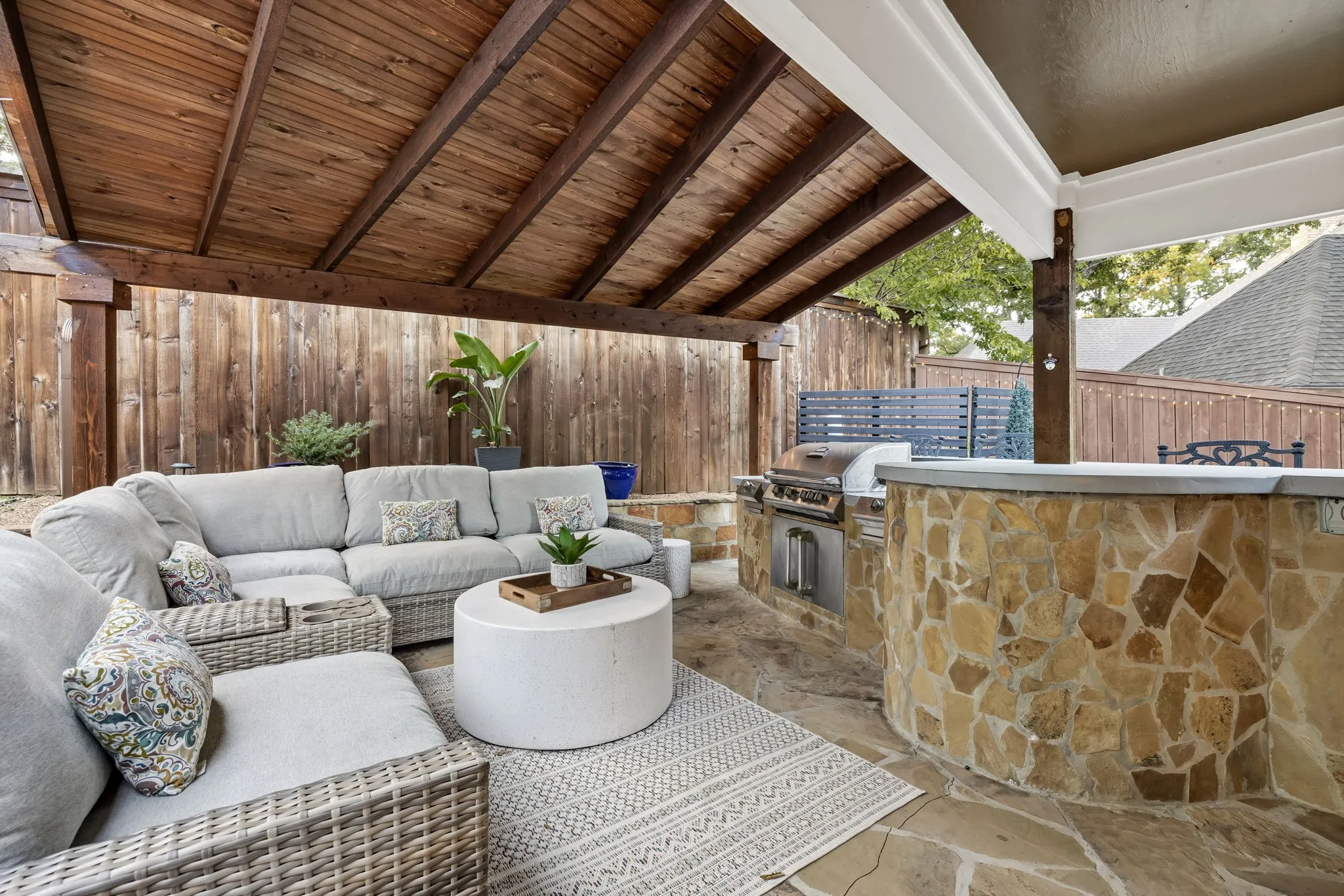 Covered patio with a wood-plank ceiling, flagstone flooring, and a stone-clad outdoor kitchen