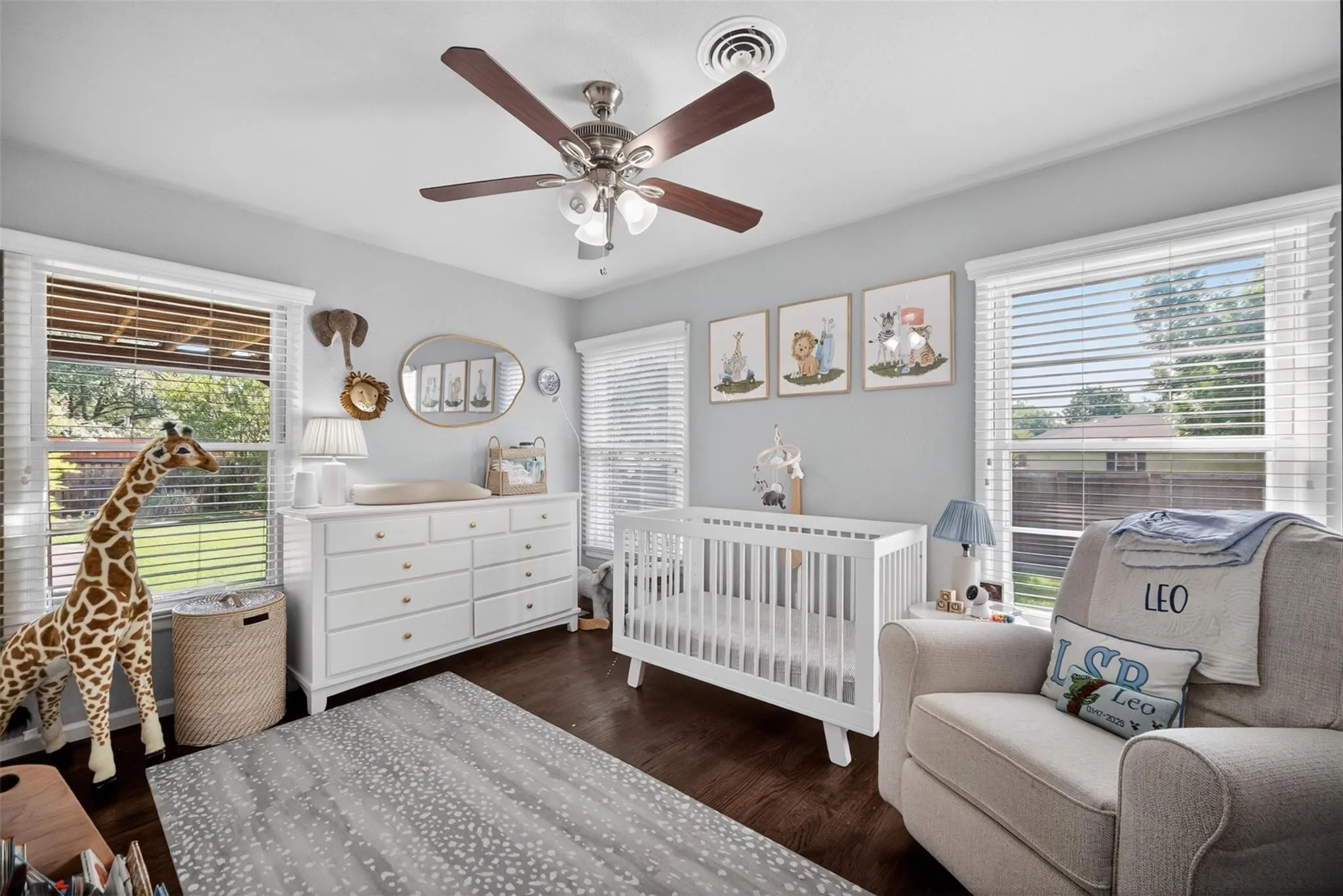 Dark wood-finish flooring, white window blinds, and a ceiling fan with light fixture