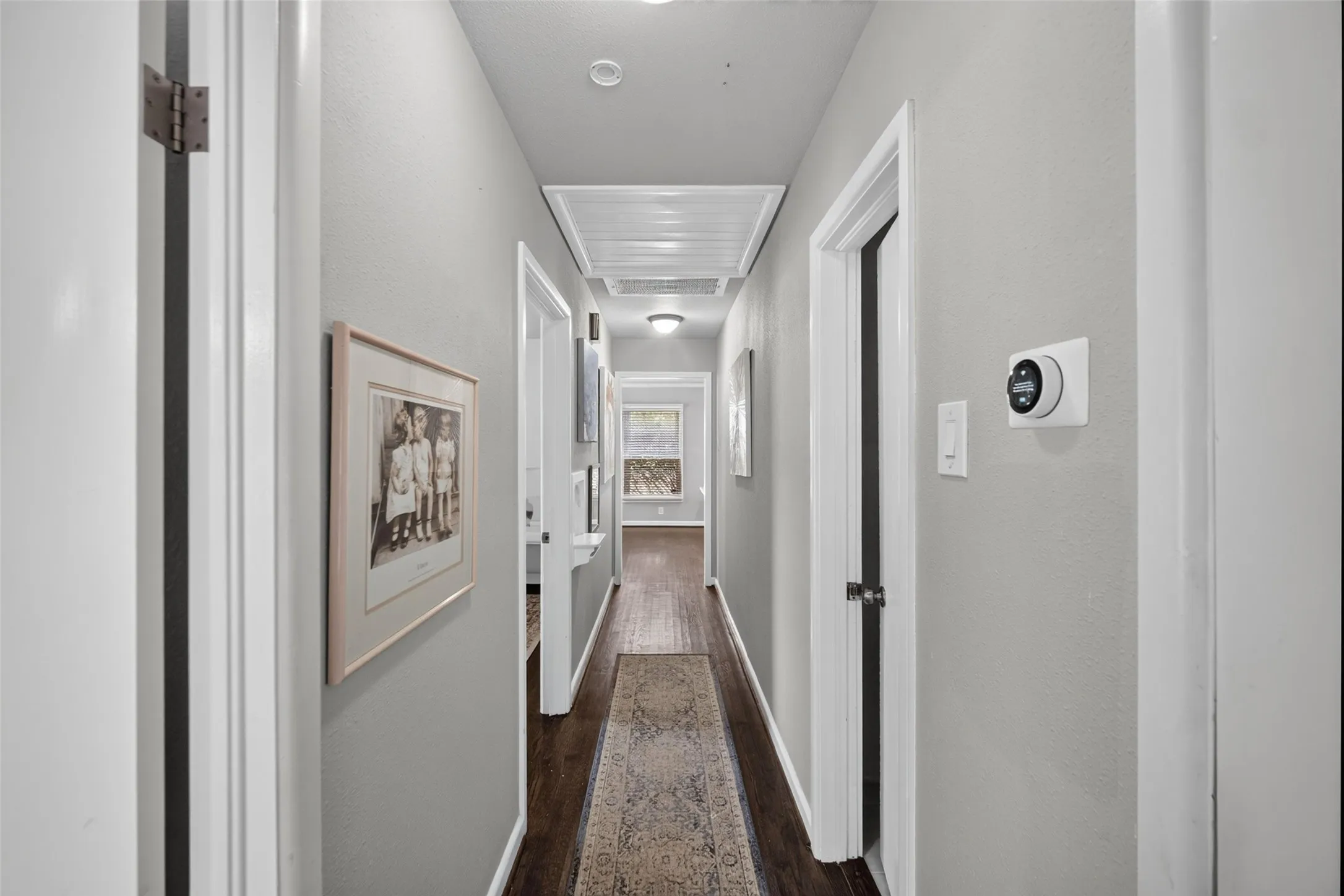 Hallway featuring recessed lighting, dark wood-finish flooring, white baseboards, and a wall-mounted thermostat