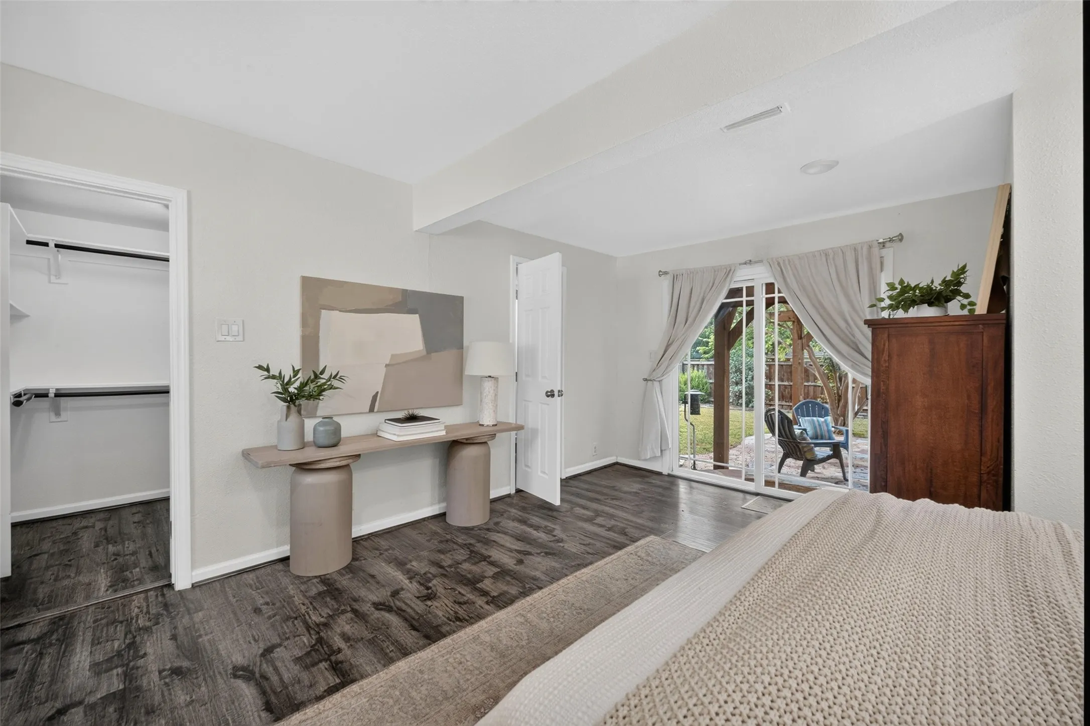 Wood-finish flooring throughout, white walls, built-in closet with shelving and hanging rods, and glass patio doors