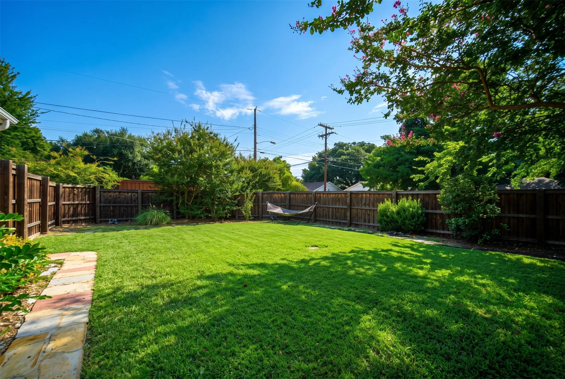 Expansive backyard with a manicured lawn, established privacy fencing, and mature perimeter landscaping