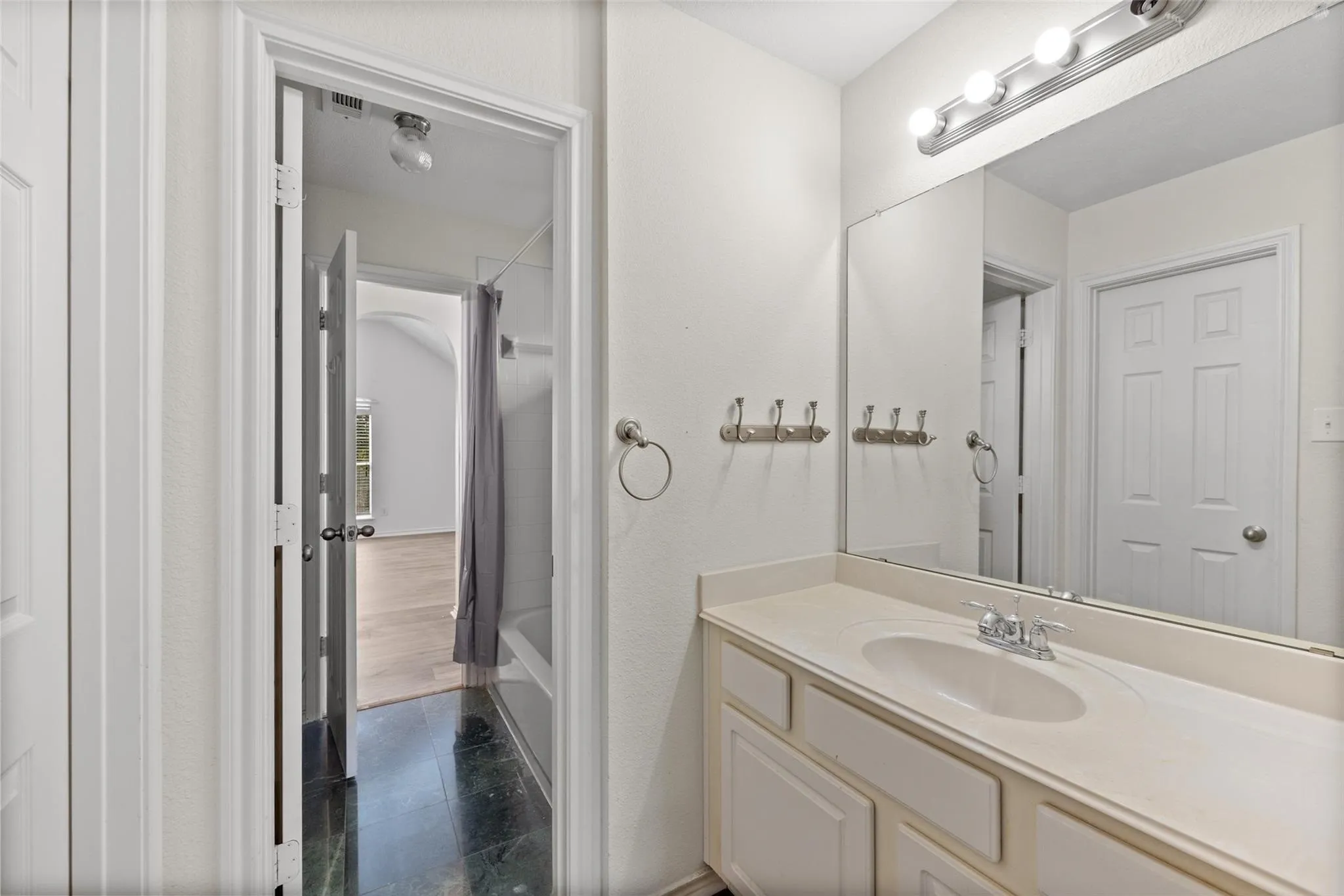 Vanity with integrated sink, expansive wall-mounted mirror, and overhead strip lighting