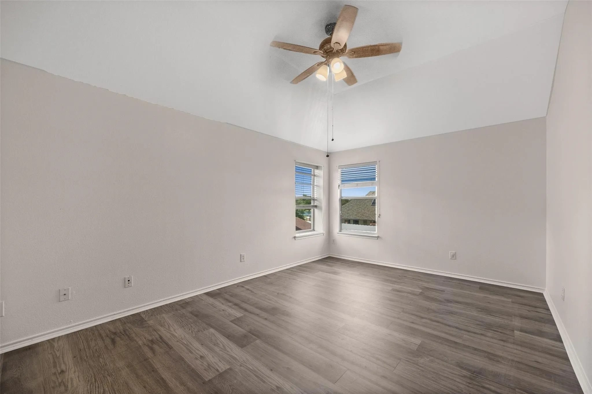 Vaulted ceiling, wood-finish flooring, ceiling fan with light fixture, and dual windows