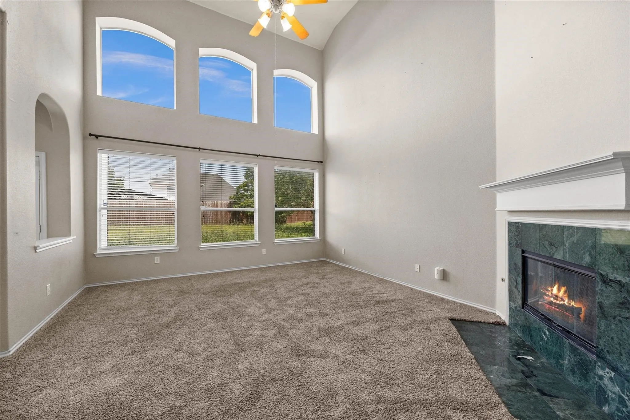 Two-story living area with arched transom windows and a ceiling fan