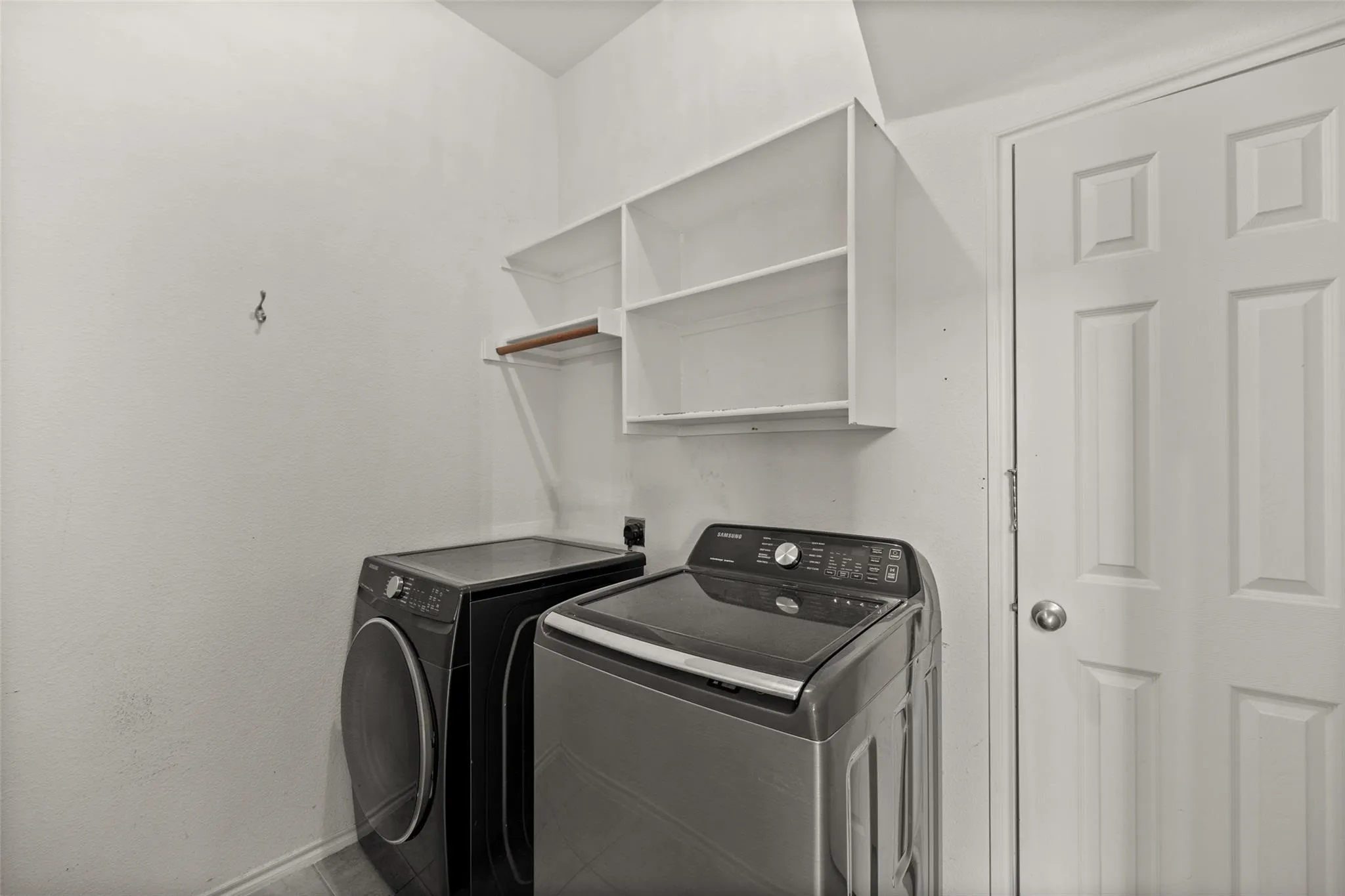 Laundry area with built-in open shelving and a wood-finish hanging rod