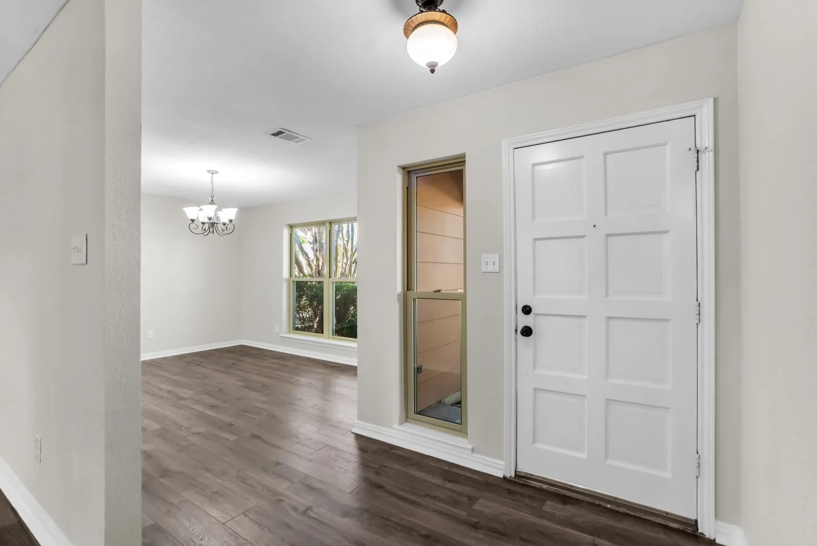 Entry foyer with wood-finish flooring, a paneled front door, and an adjacent sidelight window