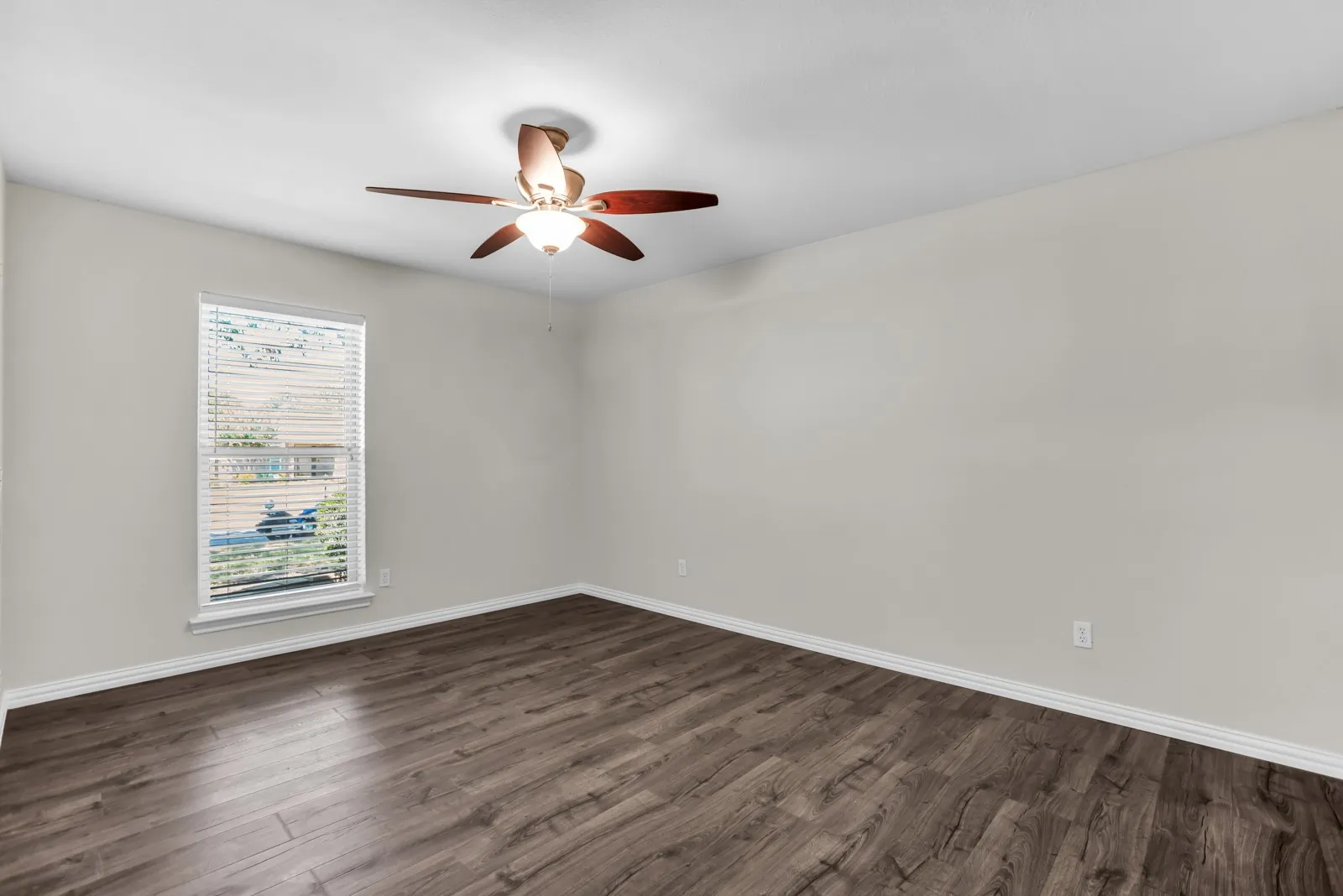 Room featuring wood-finish flooring, a window with horizontal blinds, and a ceiling fan with integrated lighting