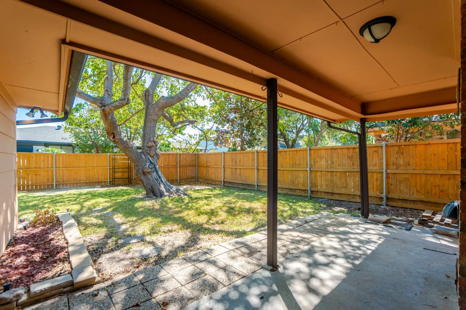 Covered patio with an outdoor light fixture, concrete flooring, and support columns