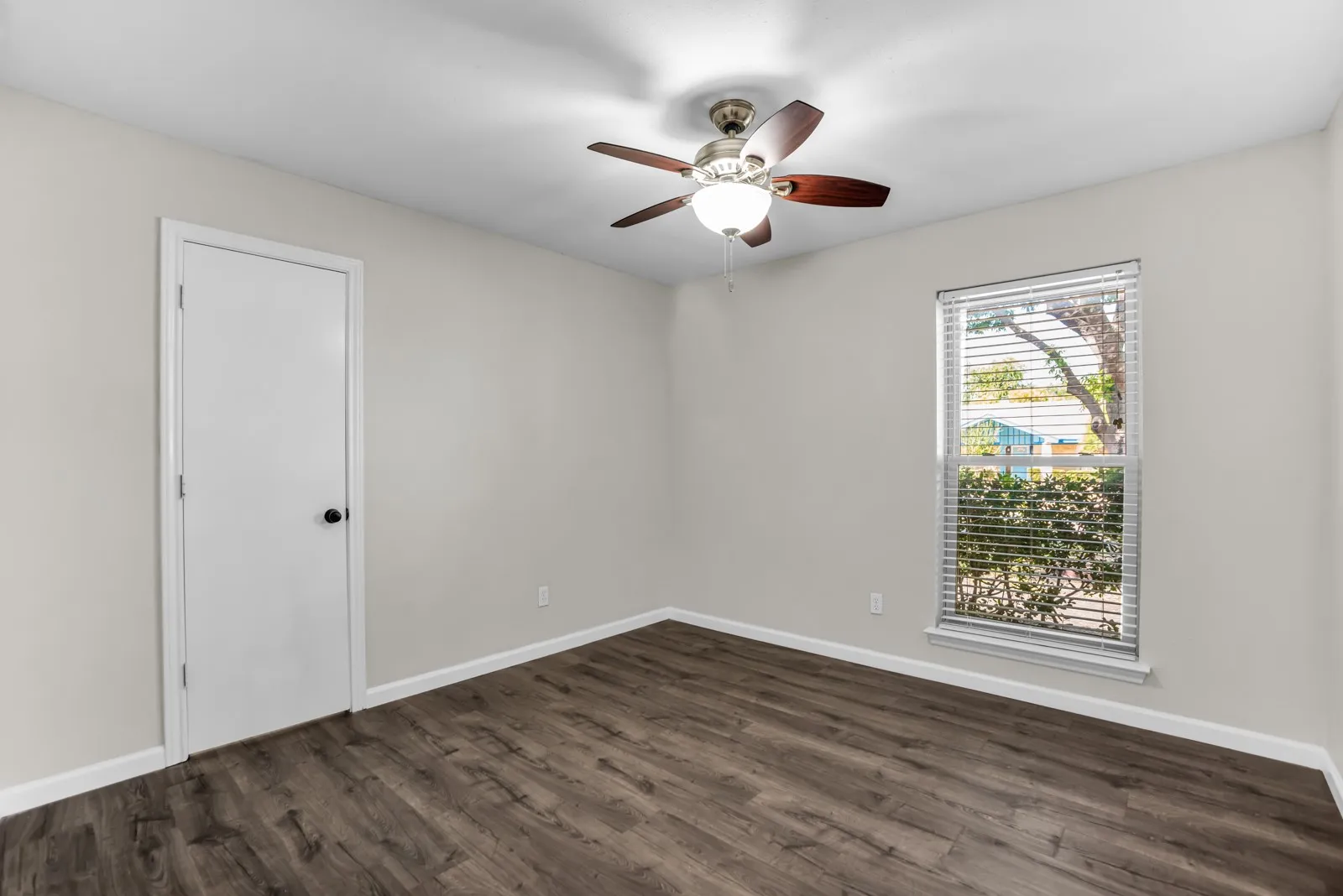 Neutral wall paint, wood-finish flooring, and a ceiling fan with light fixture