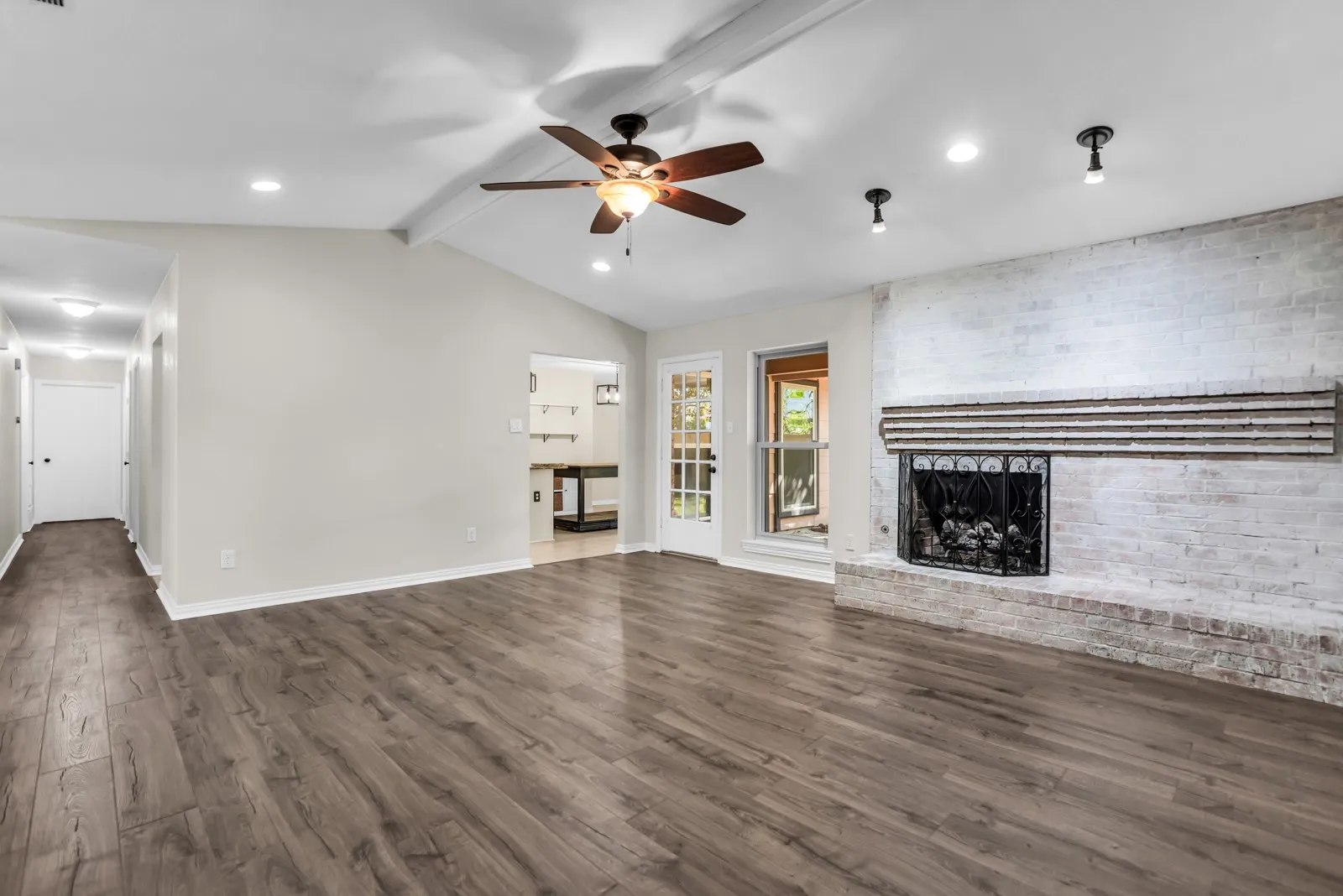 Vaulted ceiling with a ceiling fan, recessed lighting, wood-finish flooring, and a whitewashed brick fireplace