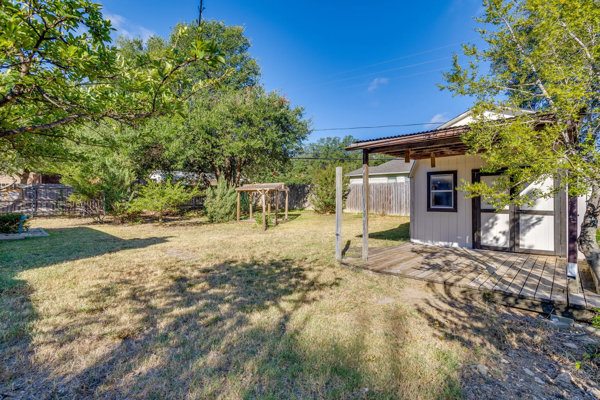 Expansive yard featuring a detached shed with a covered wood-finish deck and corrugated metal roof