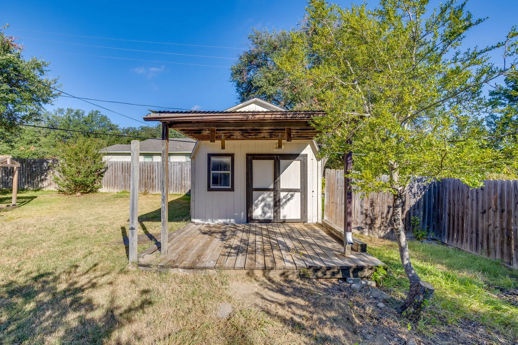 Detached shed with corrugated metal roofing, an exterior window, and a wood deck
