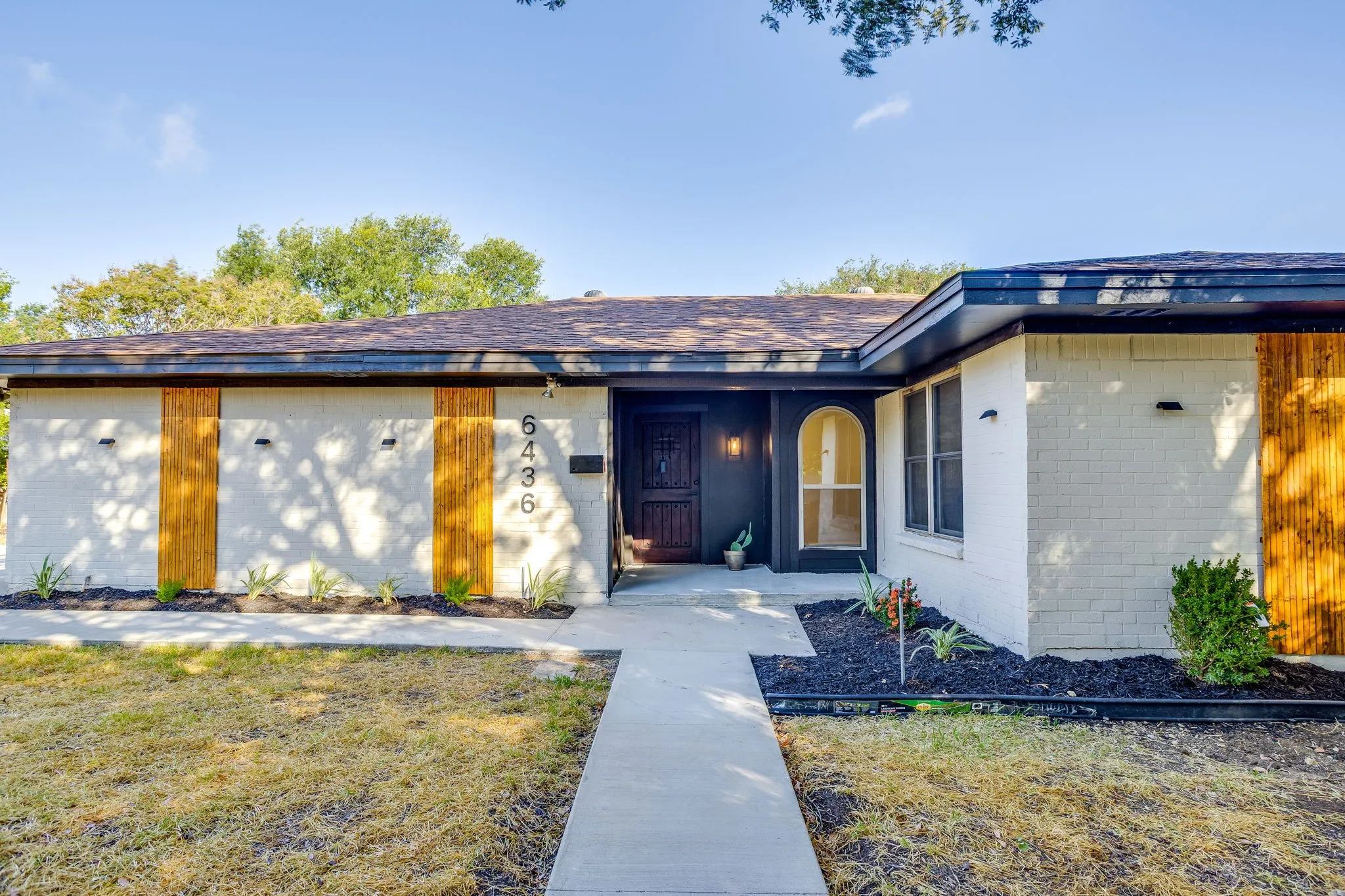 Brick exterior with wood accents, arched front window, and dark wood entry door