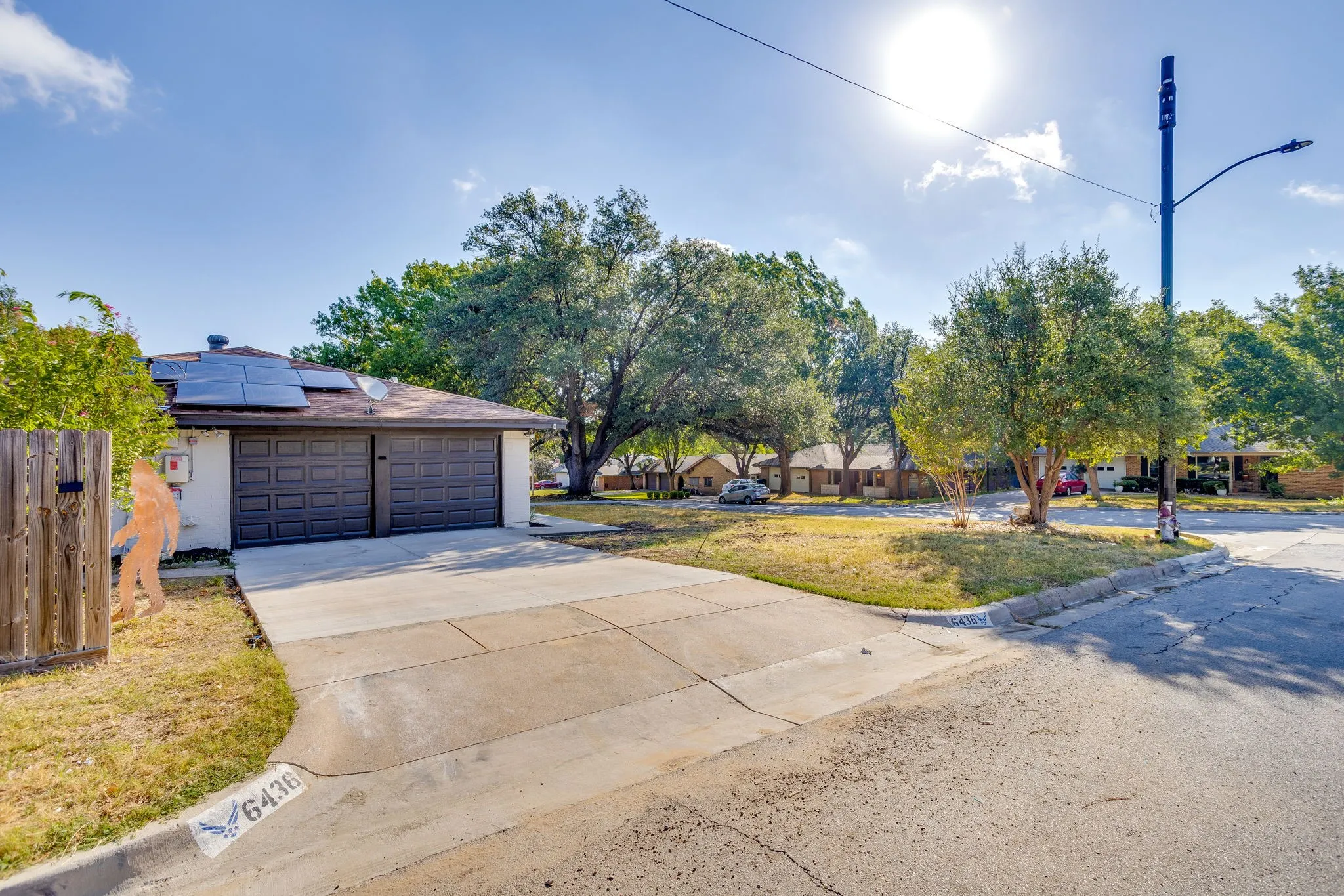 Front exterior with solar panels, two-car garage, and concrete driveway