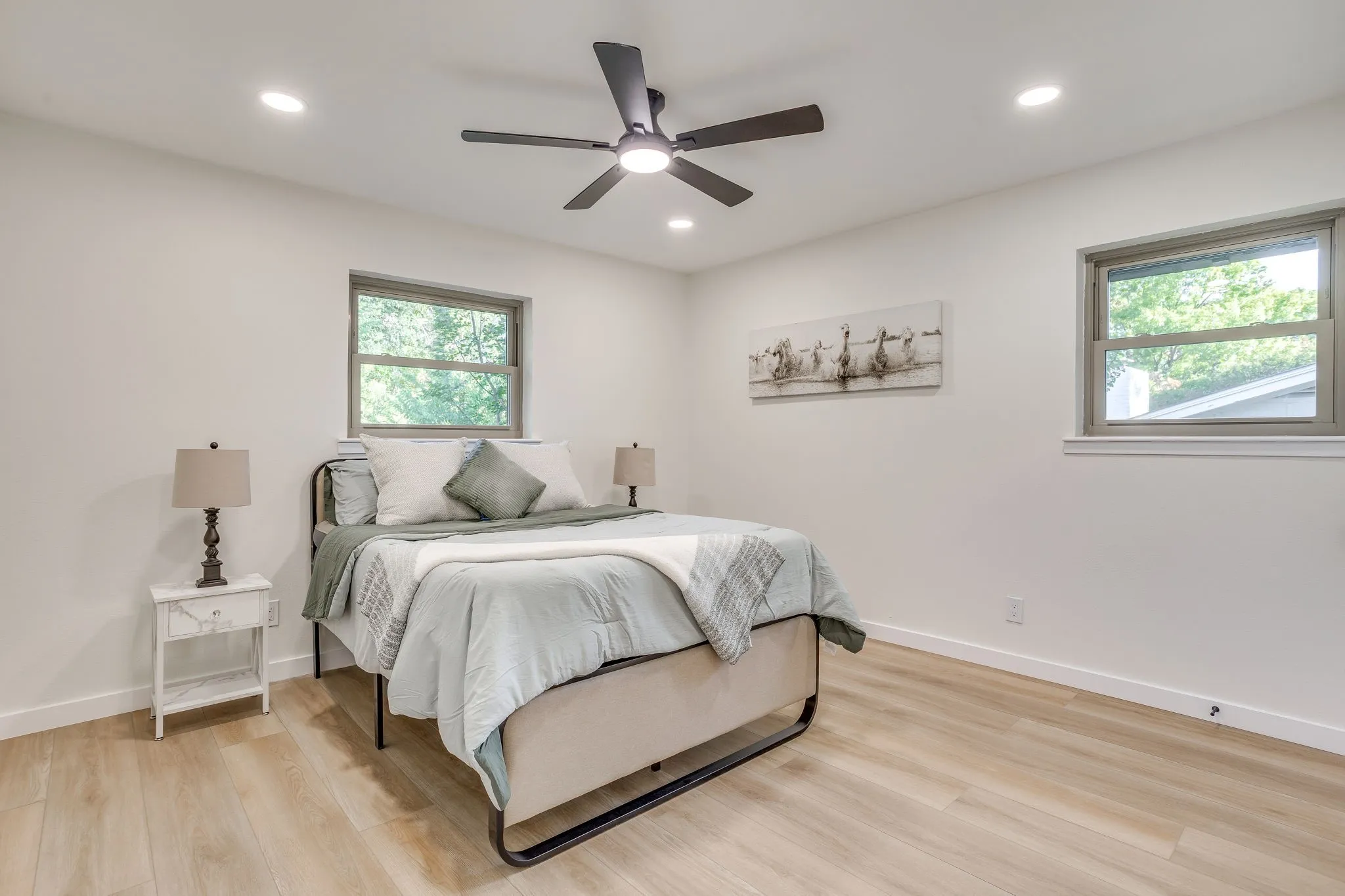 Wood-finish flooring, recessed lighting, ceiling fan with integrated light, and multiple windows