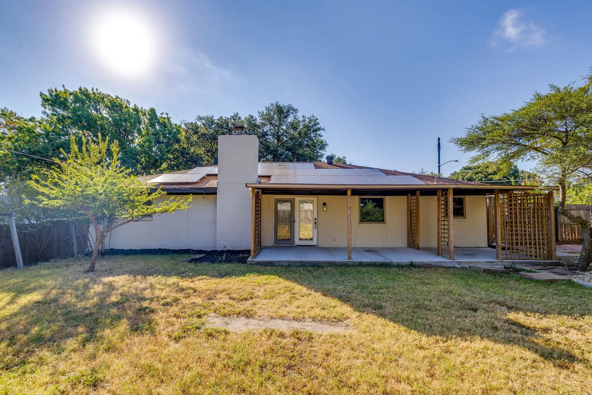 Covered patio with wood support beams, privacy lattice, and concrete flooring
