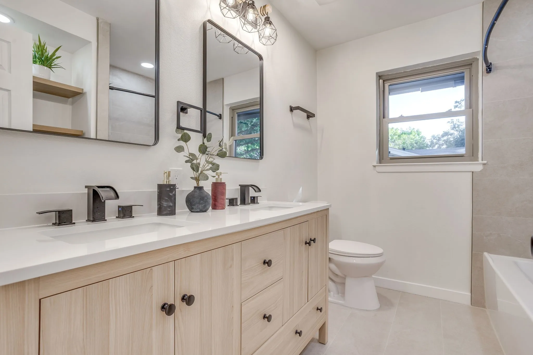 Dual vanity with light wood-finish cabinetry and white countertops