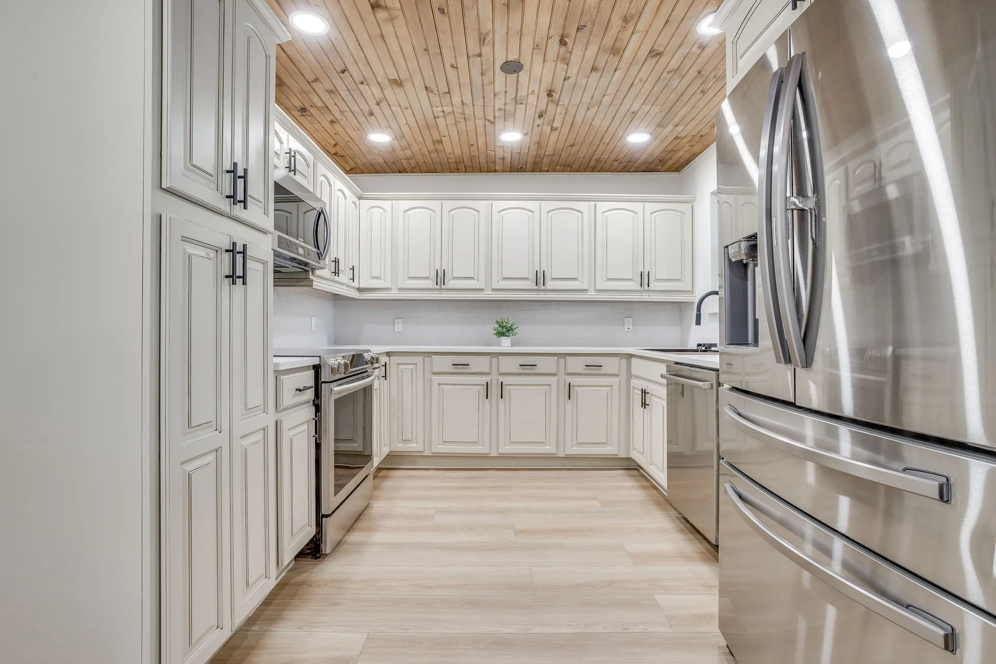 Kitchen featuring stainless steel appliances, wood-finish ceiling, recessed lighting, white cabinetry with dark hardware, and light-toned wood-finish flooring