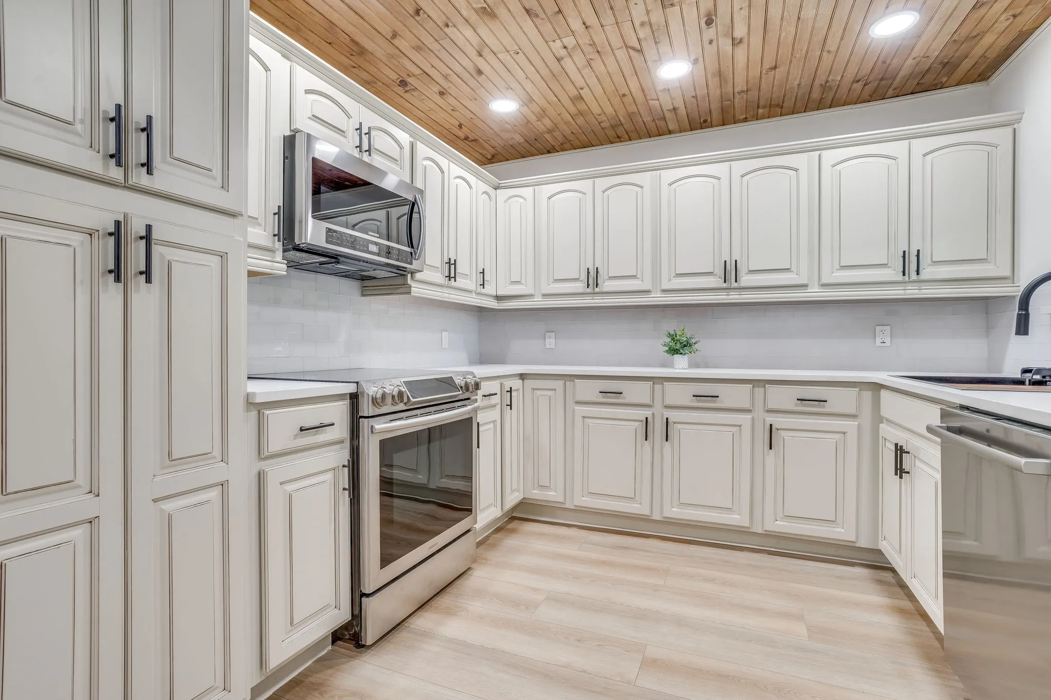 Kitchen featuring extensive white cabinetry, stainless steel appliances, wood-finish flooring, white countertops, and a wood-paneled ceiling