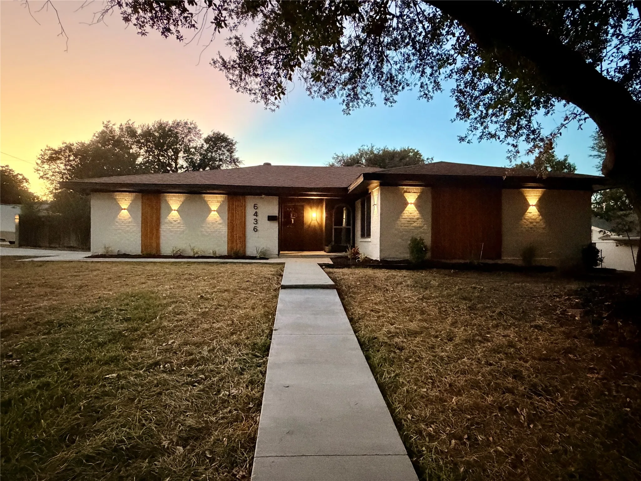 Mid-century modern facade with wood-paneled accents, brick exterior, and contemporary exterior lighting