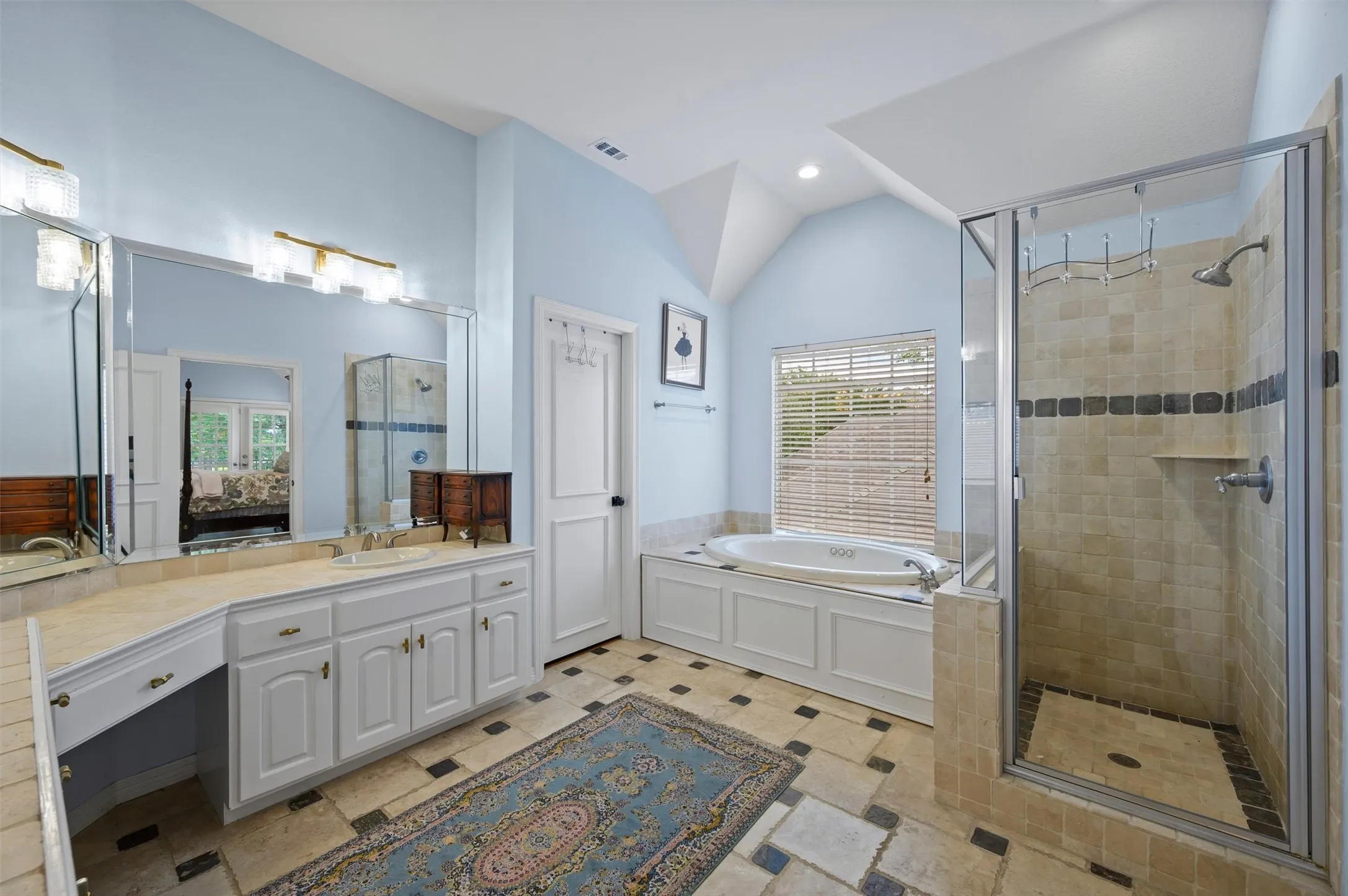 Recessed lighting illuminates a tiled walk-in shower with a glass enclosure and a built-in soaking tub