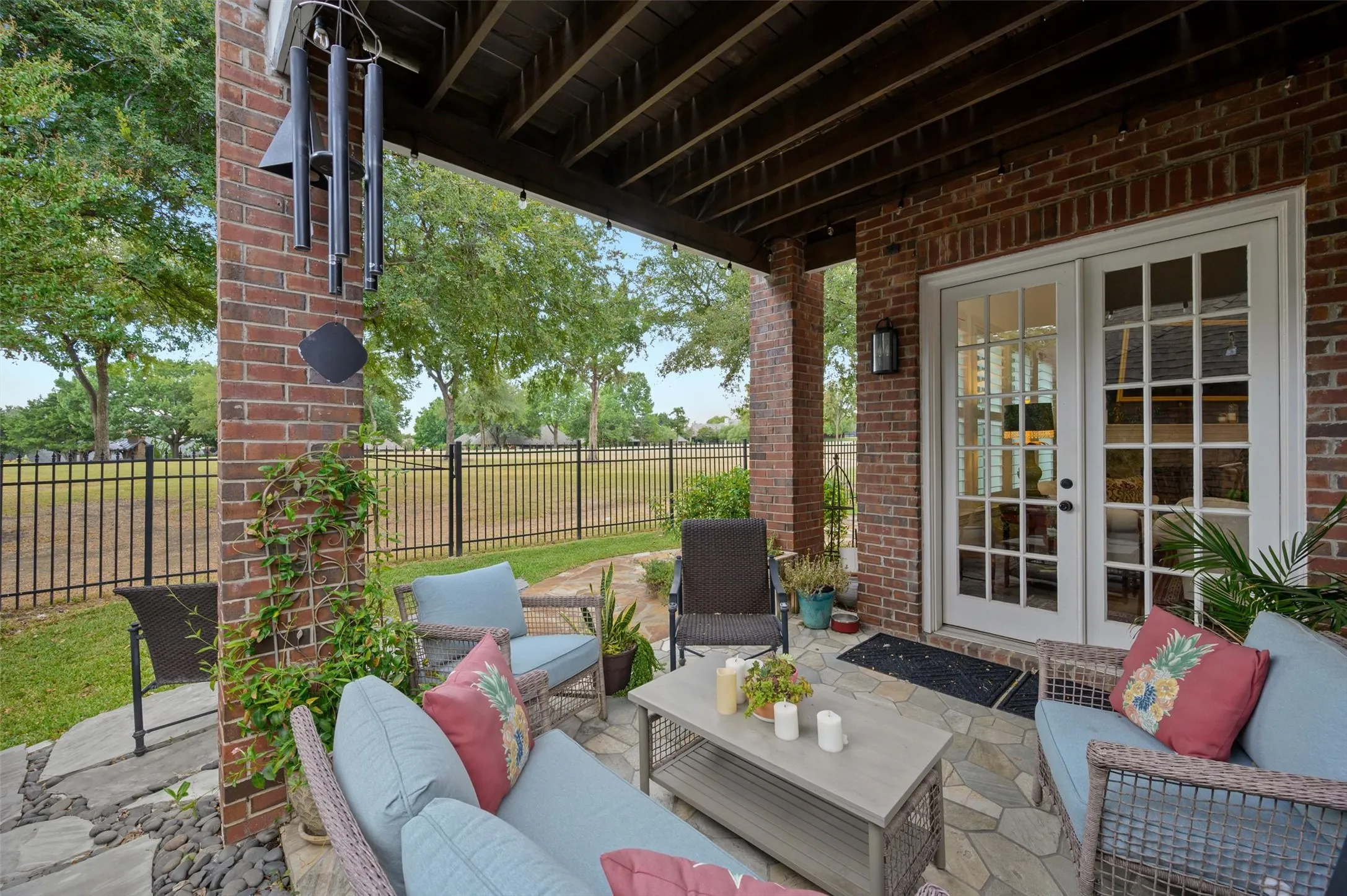 Brick-clad covered patio featuring a flagstone surface, exterior lighting, and French doors