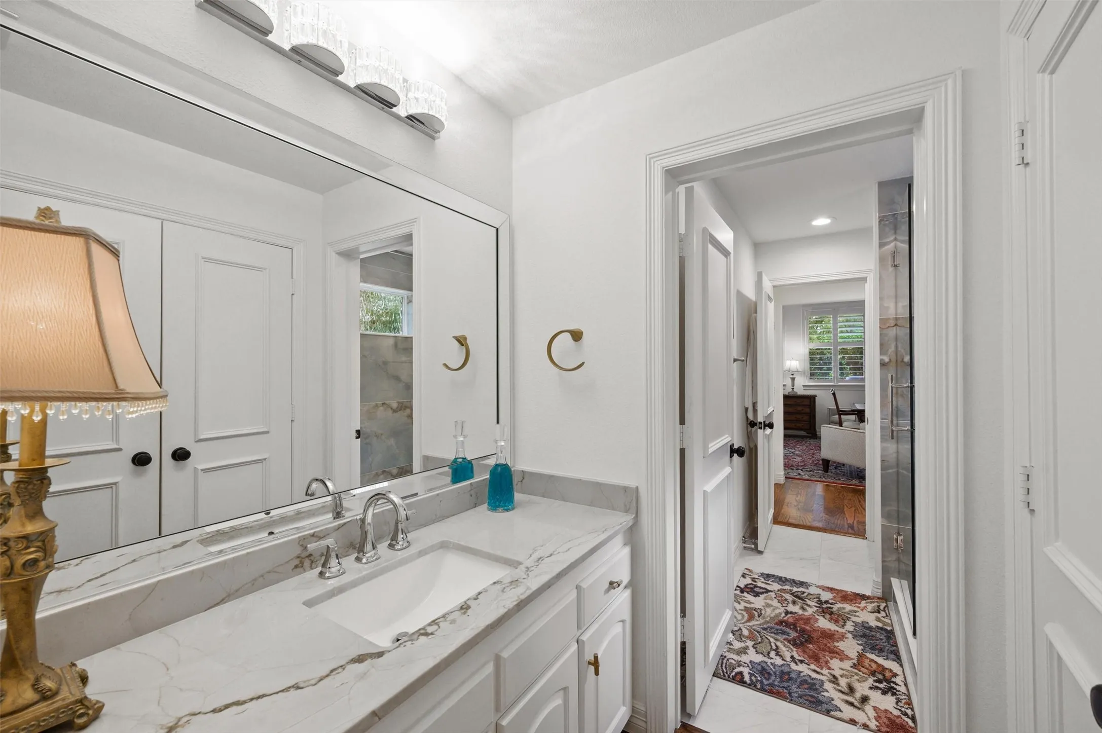 White vanity with a rectangular undermount sink, brushed nickel faucet, and a light-toned countertop with veining