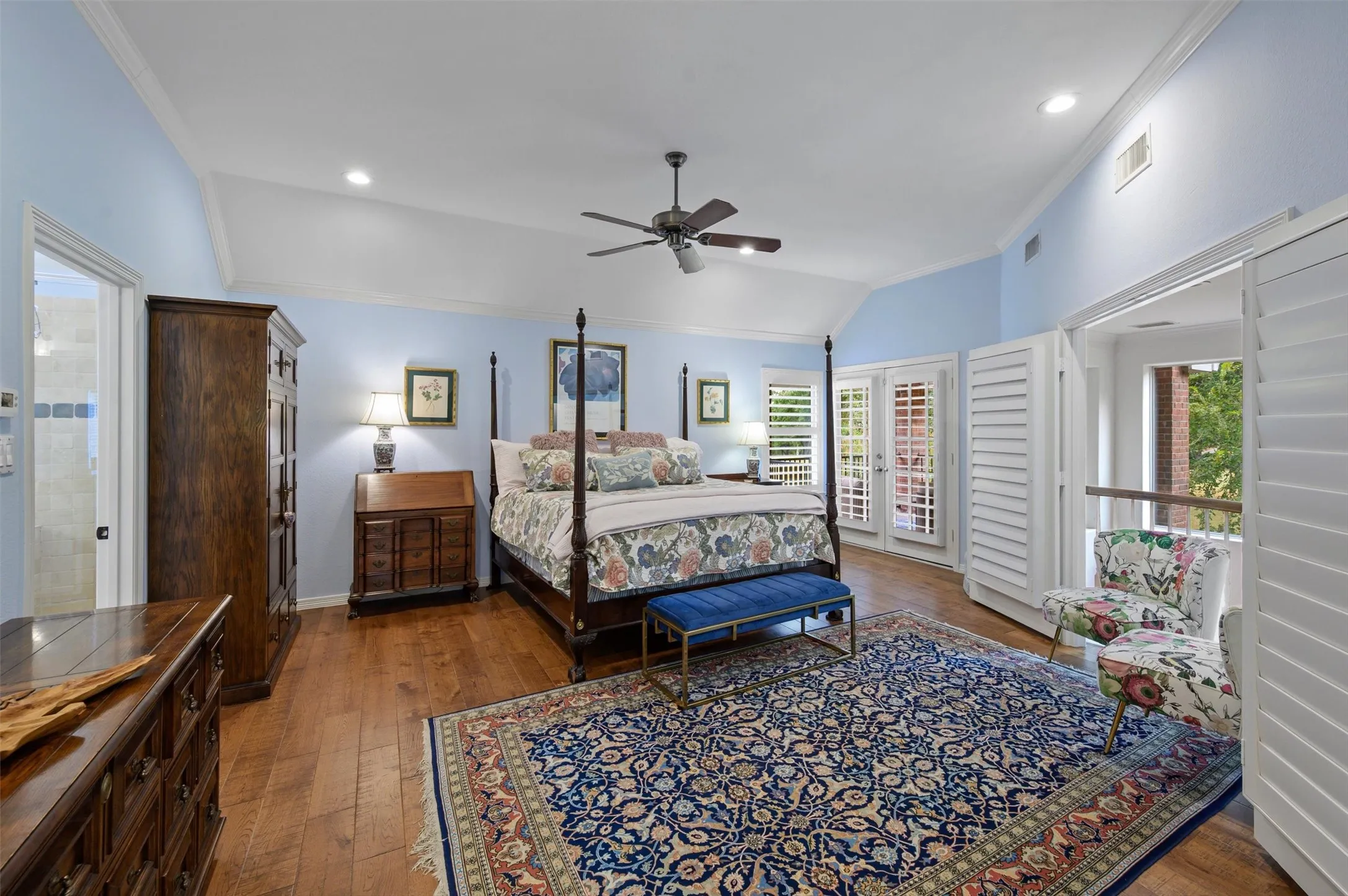 Vaulted ceiling with recessed lighting, wood-finish flooring, ceiling fan, and double doors with plantation shutters