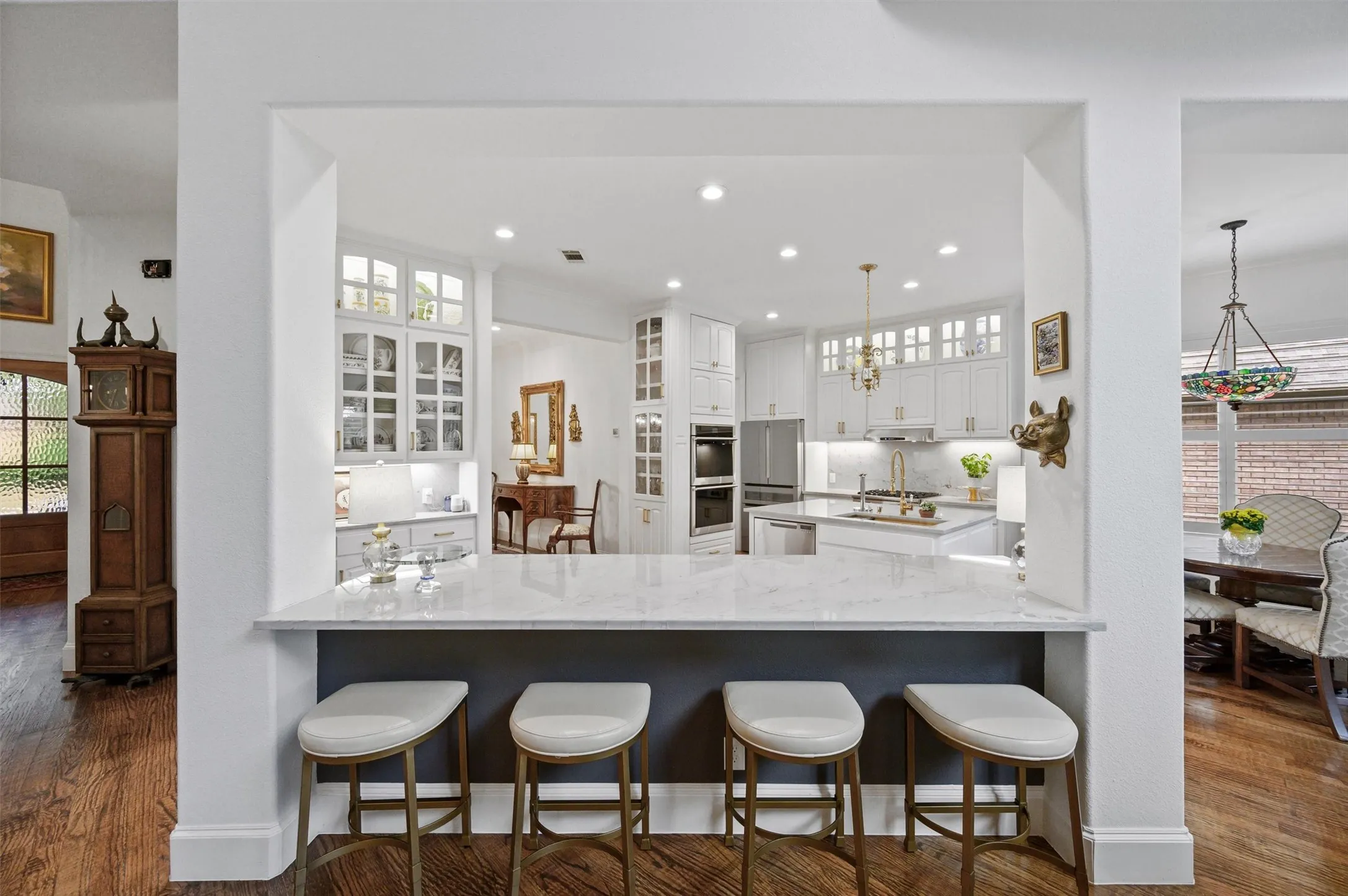 Kitchen with white cabinetry, built-in double ovens, and a central island with a sink
