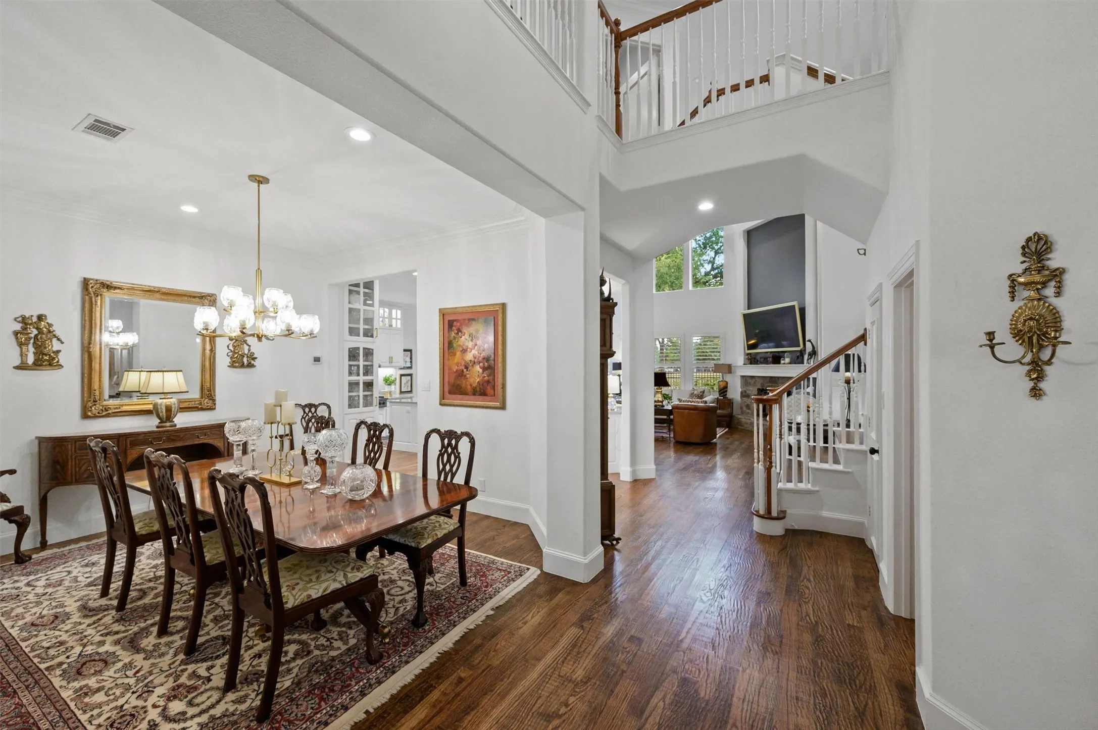 Hardwood flooring extends throughout the main level, featuring a formal dining area with a chandelier and recessed lighting