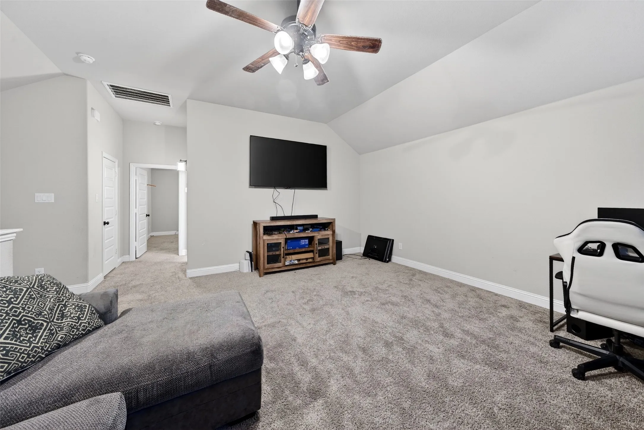 Carpeted room with vaulted ceilings, a ceiling fan, and light gray walls