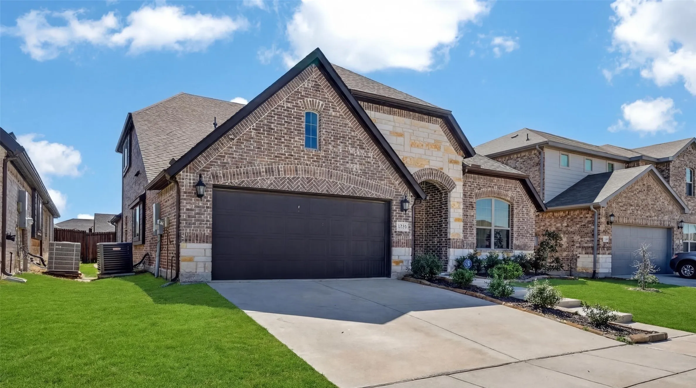 Brick and stone exterior with dark trim and an arched entry