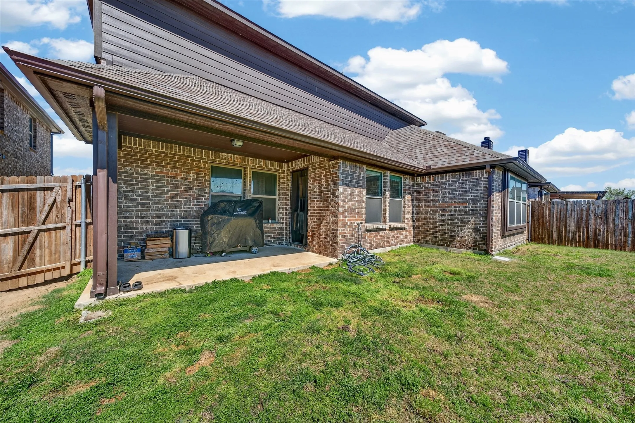 Brick exterior with a covered patio, fenced yard, and multiple windows