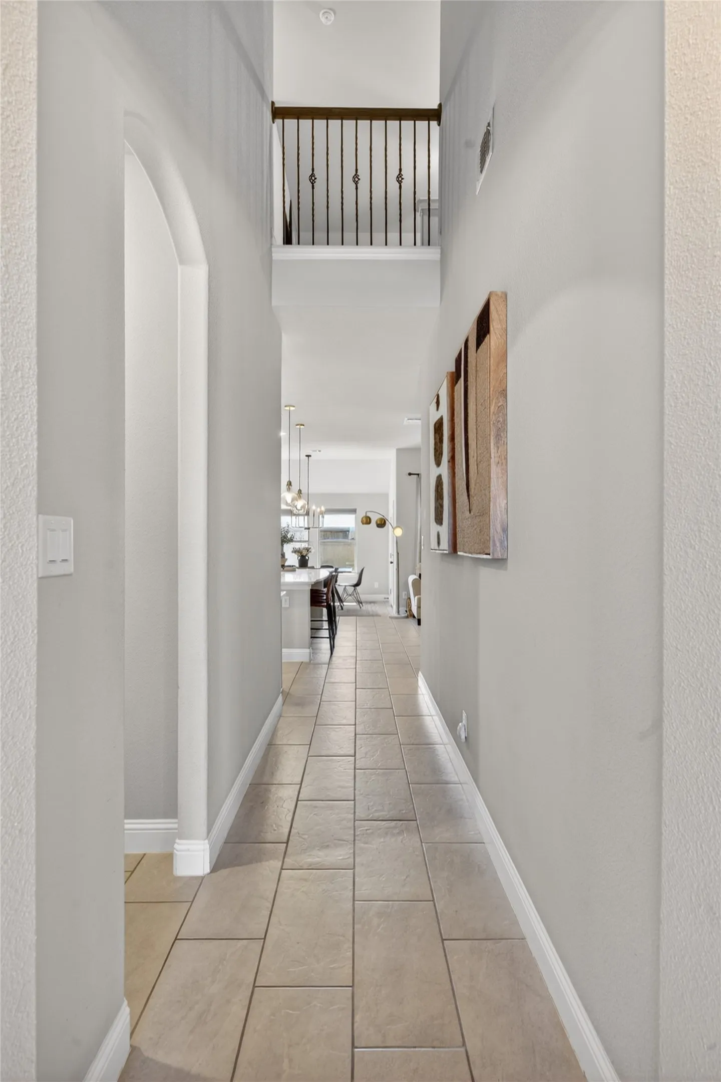 Extended hallway with neutral tile flooring, light gray walls, and an arched entryway