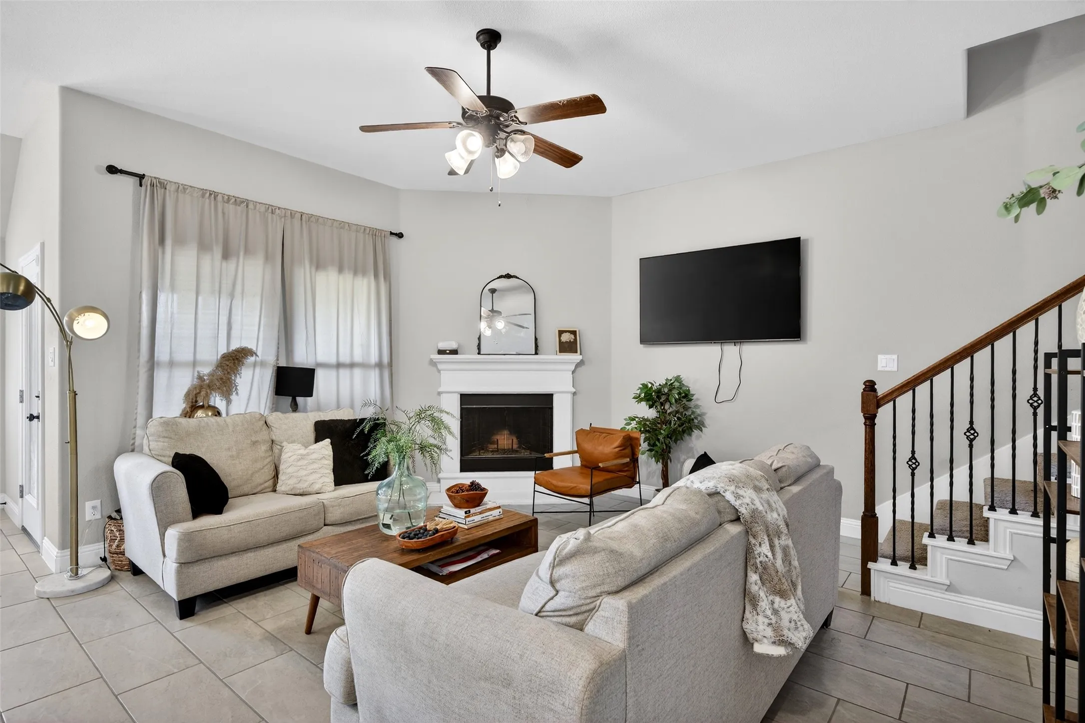 Living area featuring a fireplace with a mantel, a ceiling fan, and tile flooring