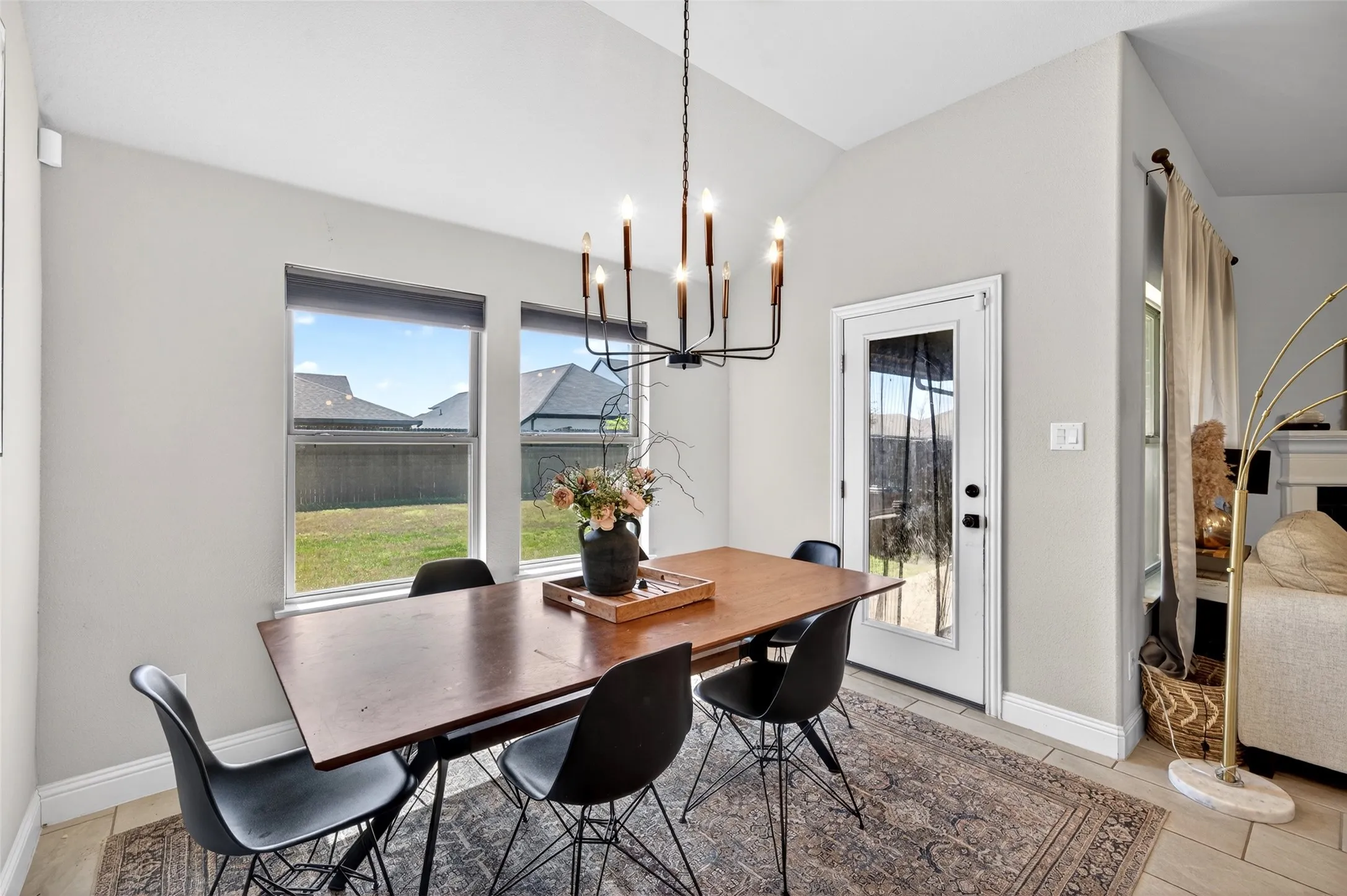 Vaulted ceiling with an elegant chandelier, large windows, and a full-light exterior door