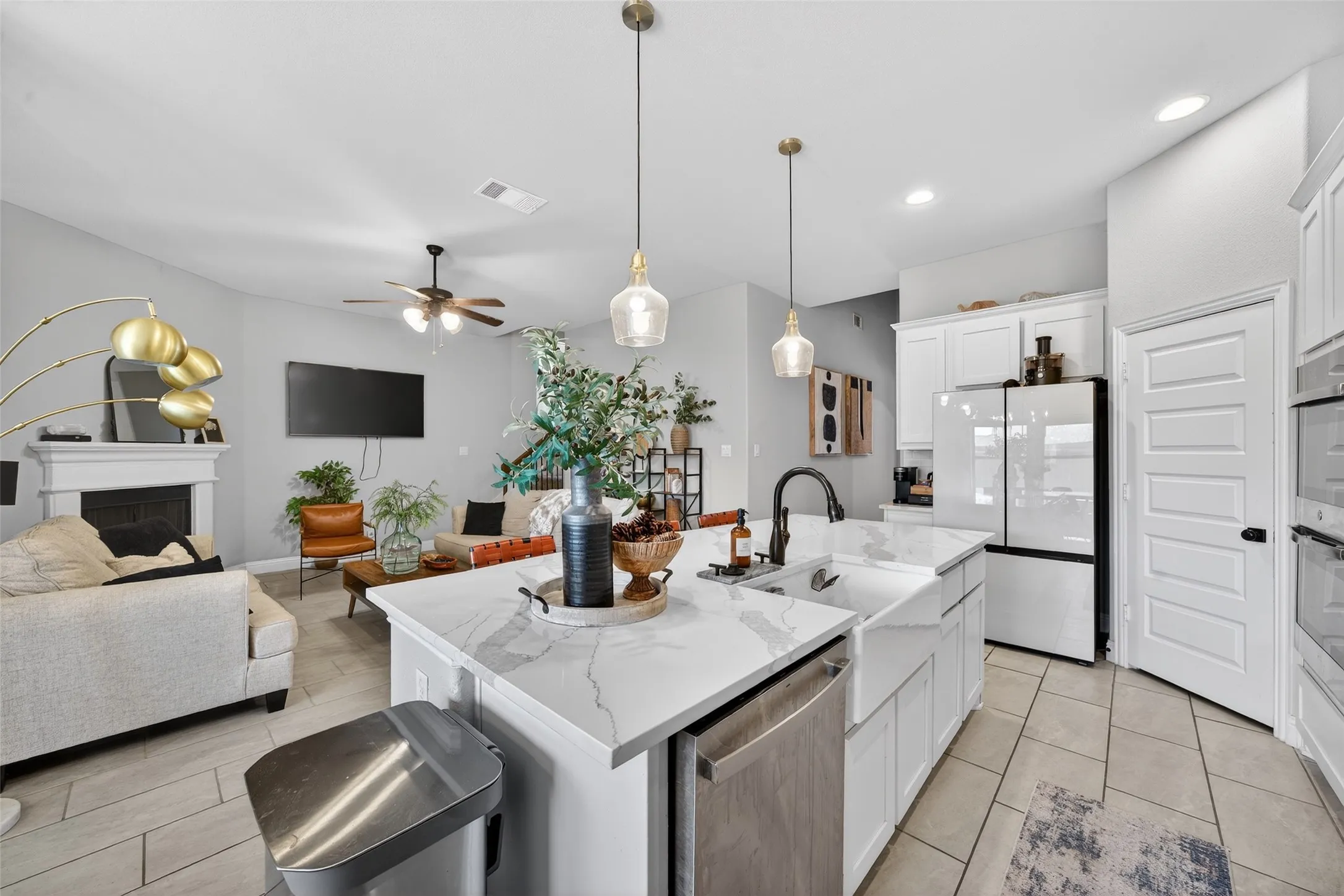 Open-concept living space with a kitchen island featuring a farmhouse sink, white cabinetry, and recessed lighting
